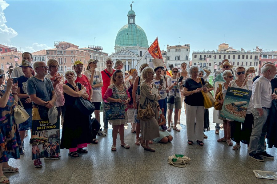 FILE - Activists gather outside Venice's Santa Lucia train station, July 13, 2024, to protest a day-tripper fee that they say has failed to dissuade visitors from arriving on peak days, as envisioned. (AP Photo/Colleen Barry, File)