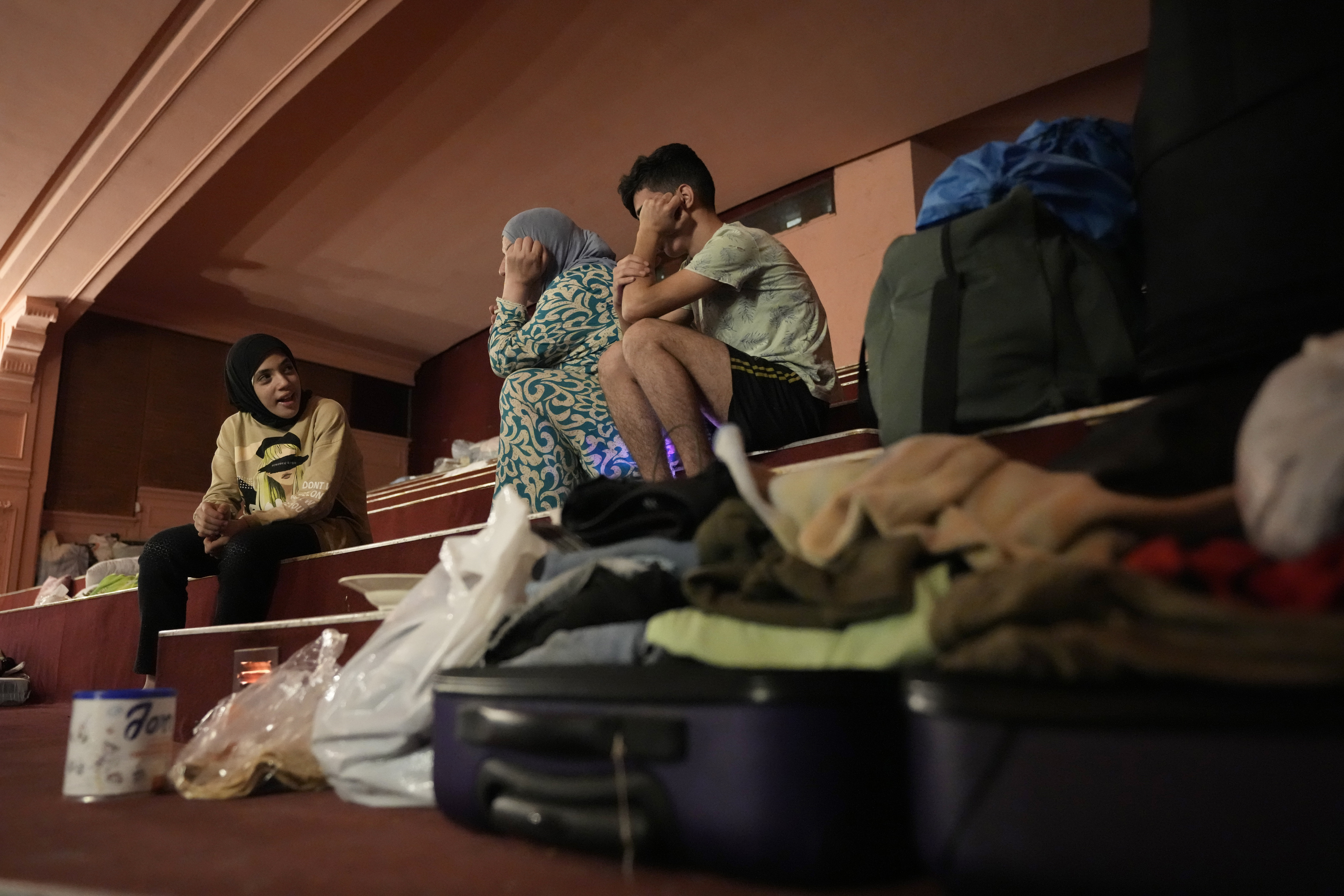 Mona Hanafi, center, who fled the ongoing Hezbollah-Israel war in south Lebanon, sits with her family, inside one of Beirut's oldest and best known movie theatres, Le Colisee, in Beirut, Lebanon, Tuesday, Oct. 22, 2024. (AP Photo/Hussein Malla)