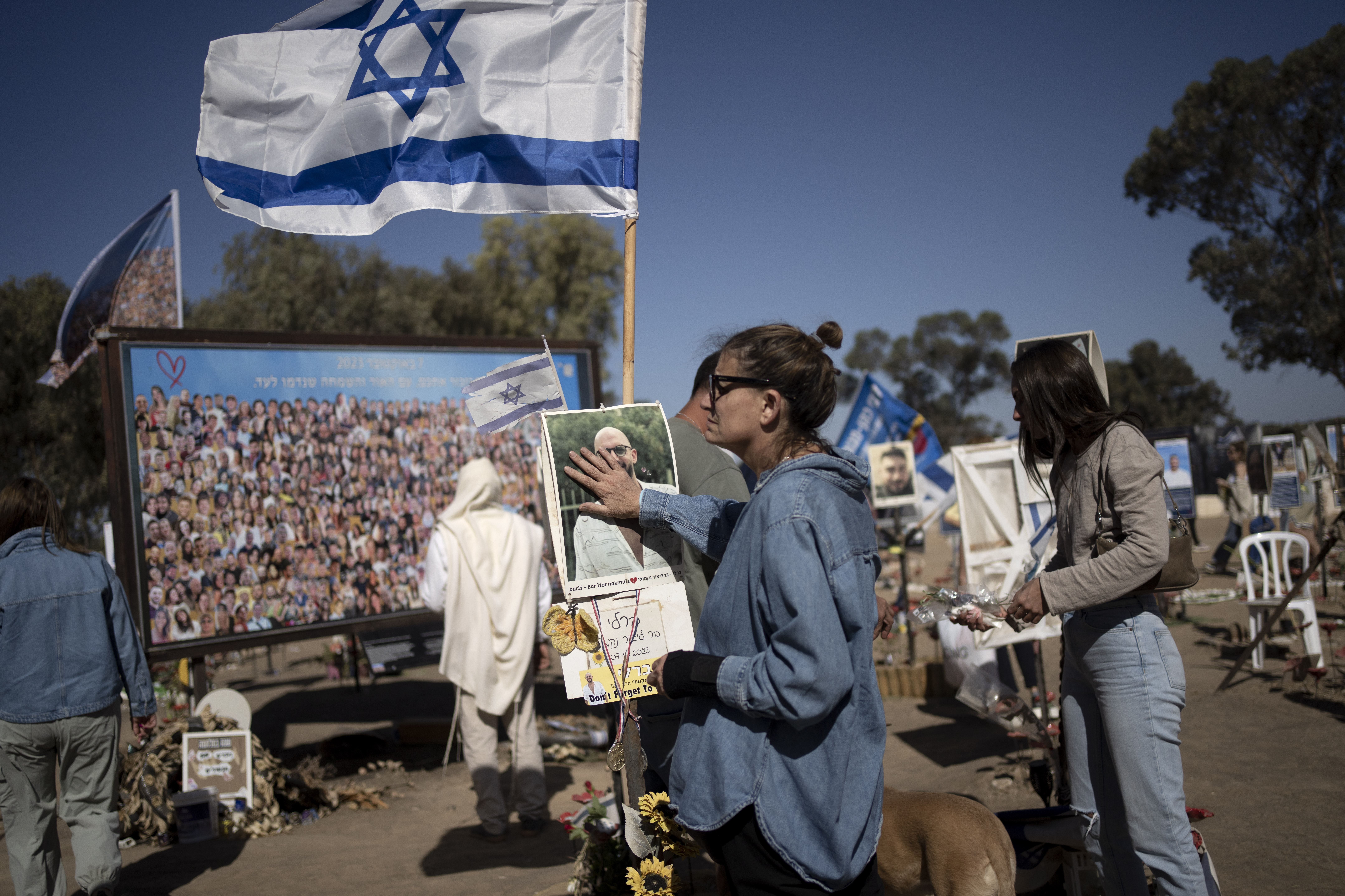 A woman pauses to touch the memorial marker of her loved one, Bar Lior Nakmuli, at the site of the Nova music festival, where hundreds of revelers were killed or kidnapped by Hamas, on the Jewish holiday of Simchat Torah, marking one year in the Hebrew calendar since the attack, near Kibbutz Re'im, southern Israel near the Gaza Strip, Thursday, Oct. 24, 2024. (AP Photo/Maya Alleruzzo)