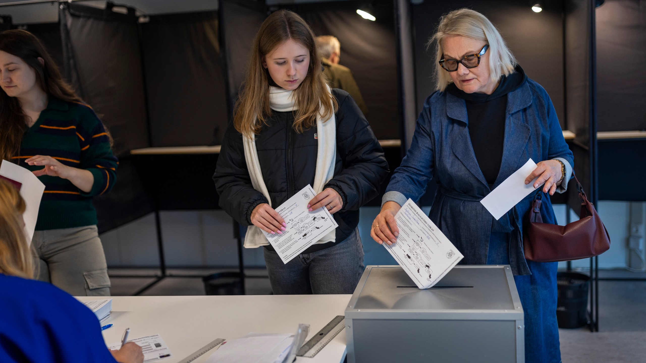 Local residents vote at a polling station during the advance voting in the second round of a parliamentary election in Vilnius, Lithuania, Tuesday, Oct. 22, 2024. (AP Photo/Mindaugas Kulbis)