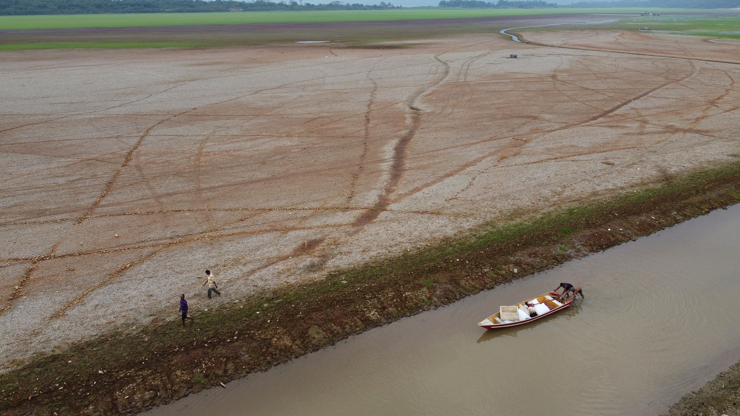 FILE - Fishermen push a boat in the Aleixo Lake amid a drought in Manaus, Amazonas state, Brazil, Sept. 24, 2024. (AP Photo/Edmar Barros, File)