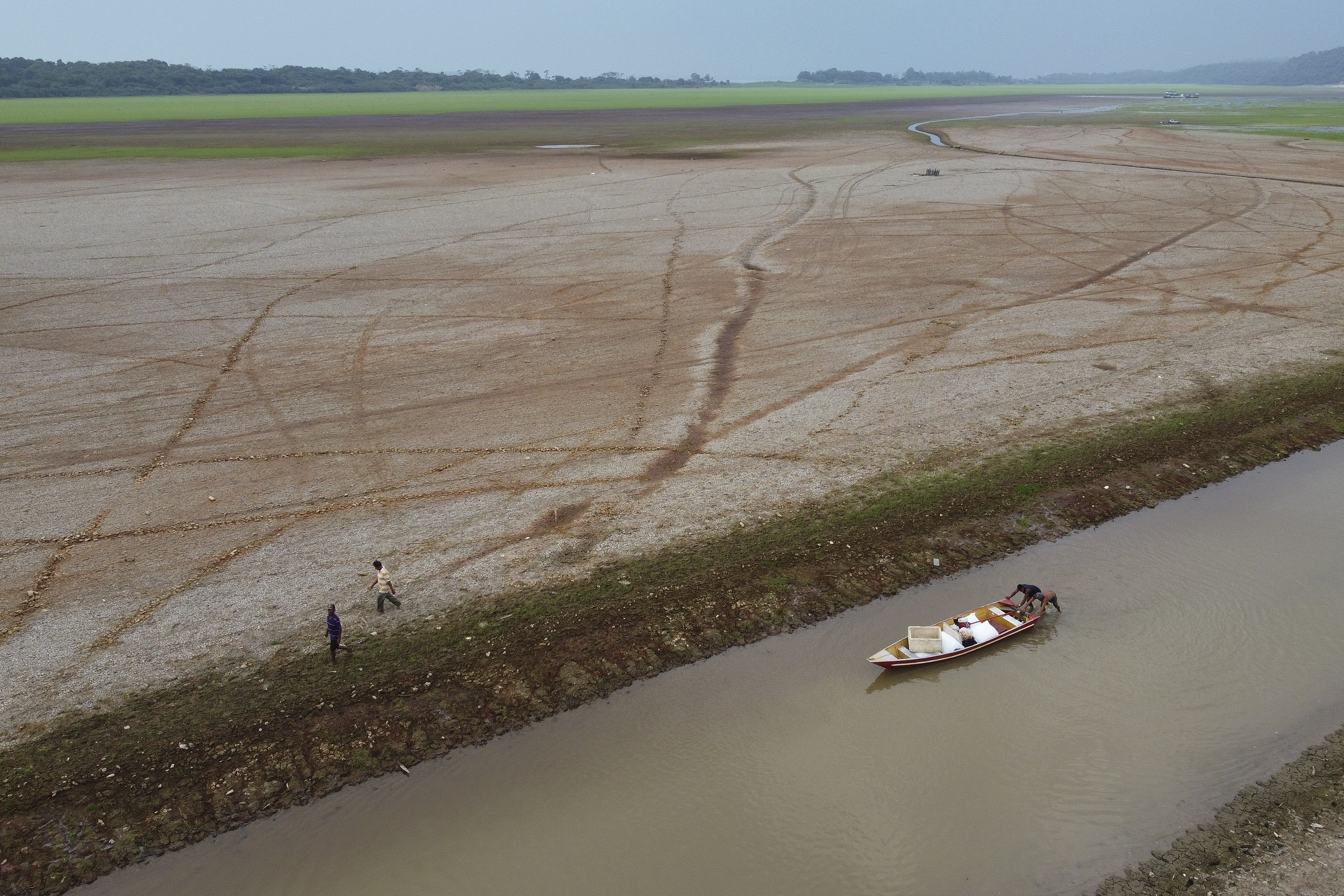 FILE - Fishermen push a boat in the Aleixo Lake amid a drought in Manaus, Amazonas state, Brazil, Sept. 24, 2024. (AP Photo/Edmar Barros, File)