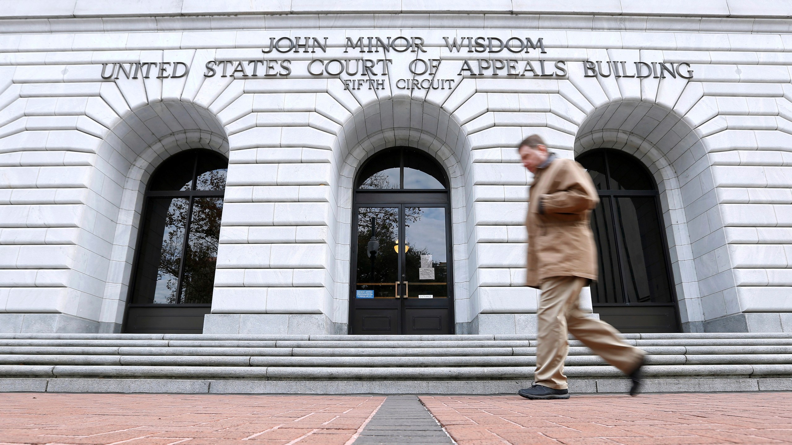 FILE - A man walks in front of the 5th U.S. Circuit Court of Appeals, Jan. 7, 2015, in New Orleans. (AP Photo/Jonathan Bachman, File)