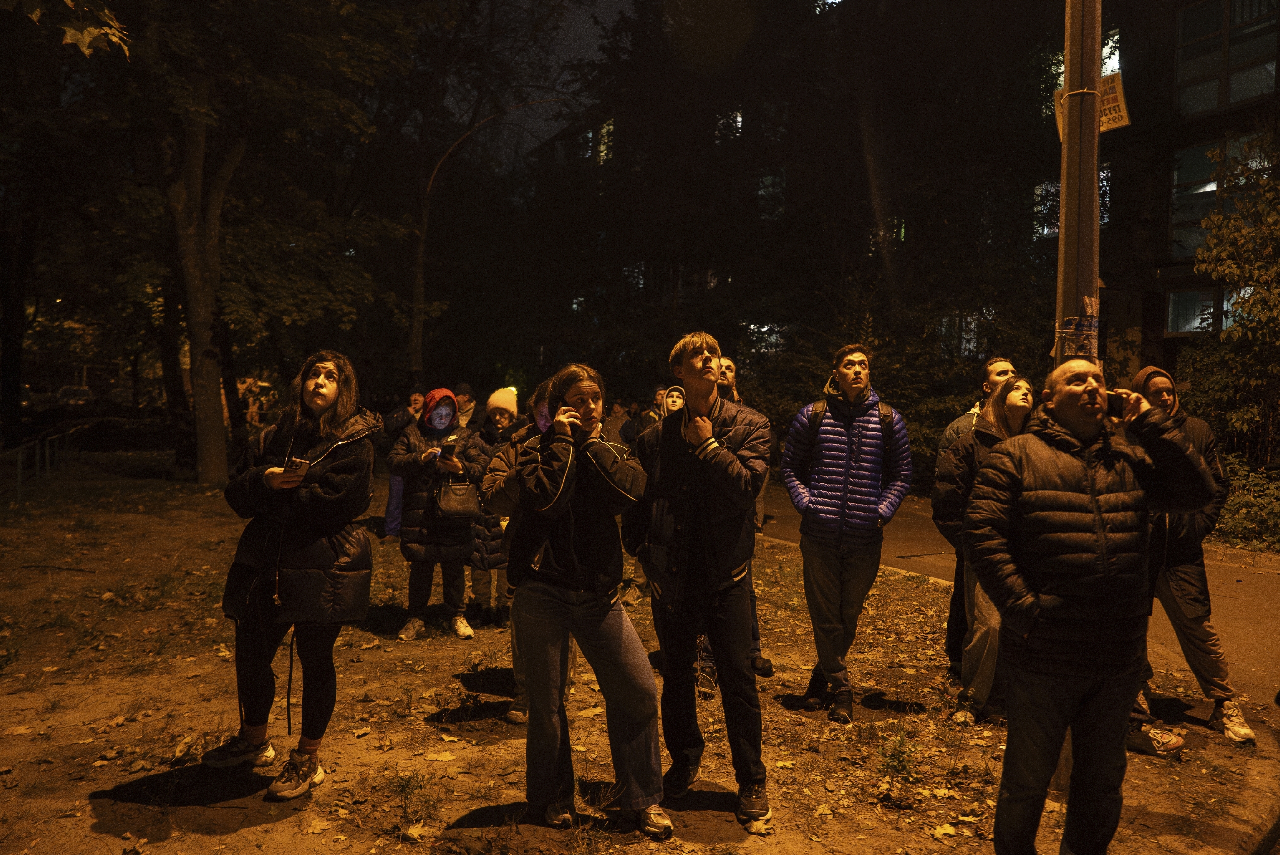 Local residents watch a residential building burn after an attack of Russian drones killed a teenager in Kyiv, Ukraine, Friday, Oct. 25, 2024. (AP Photo/Alex Babenko)