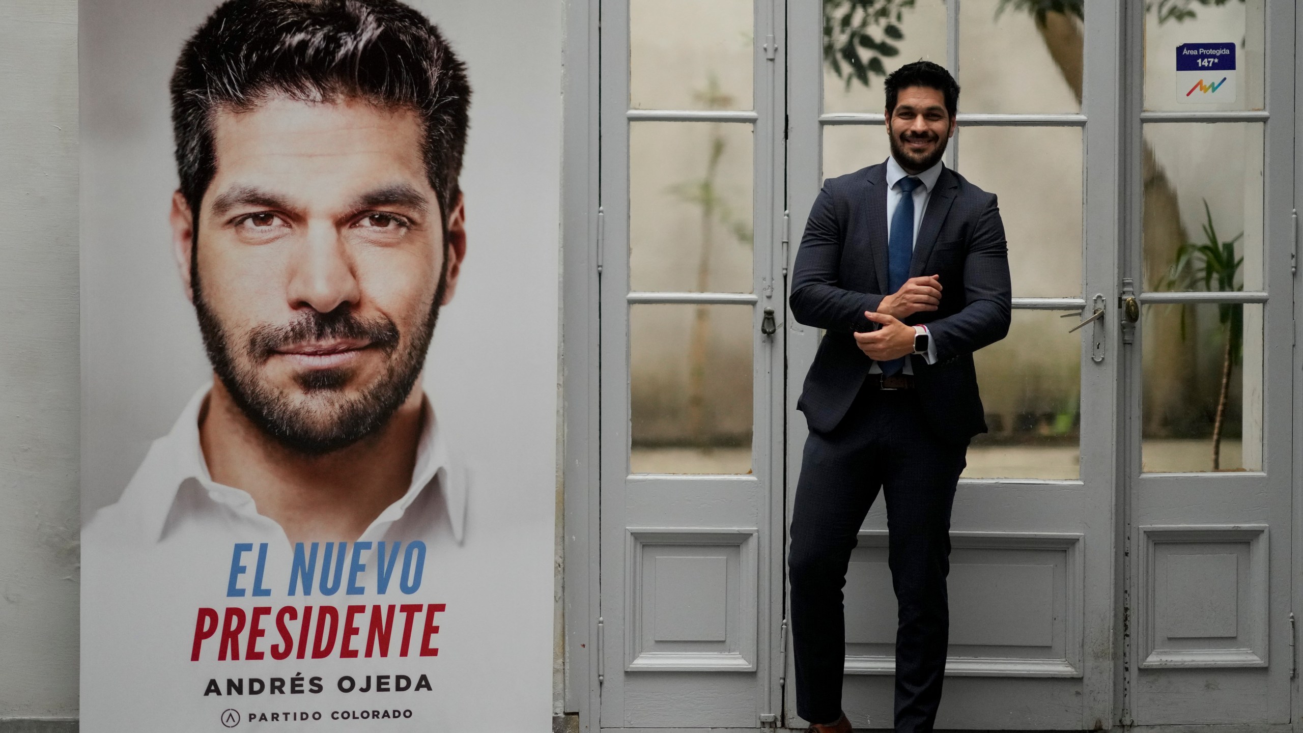 Andres Ojeda, Colorado Party presidential candidate, poses for a photo alongside one of his campaign banners, ahead of Sunday's upcoming general election, in Montevideo, Uruguay, Friday, Oct. 25, 2024. (AP Photo/Natacha Pisarenko)