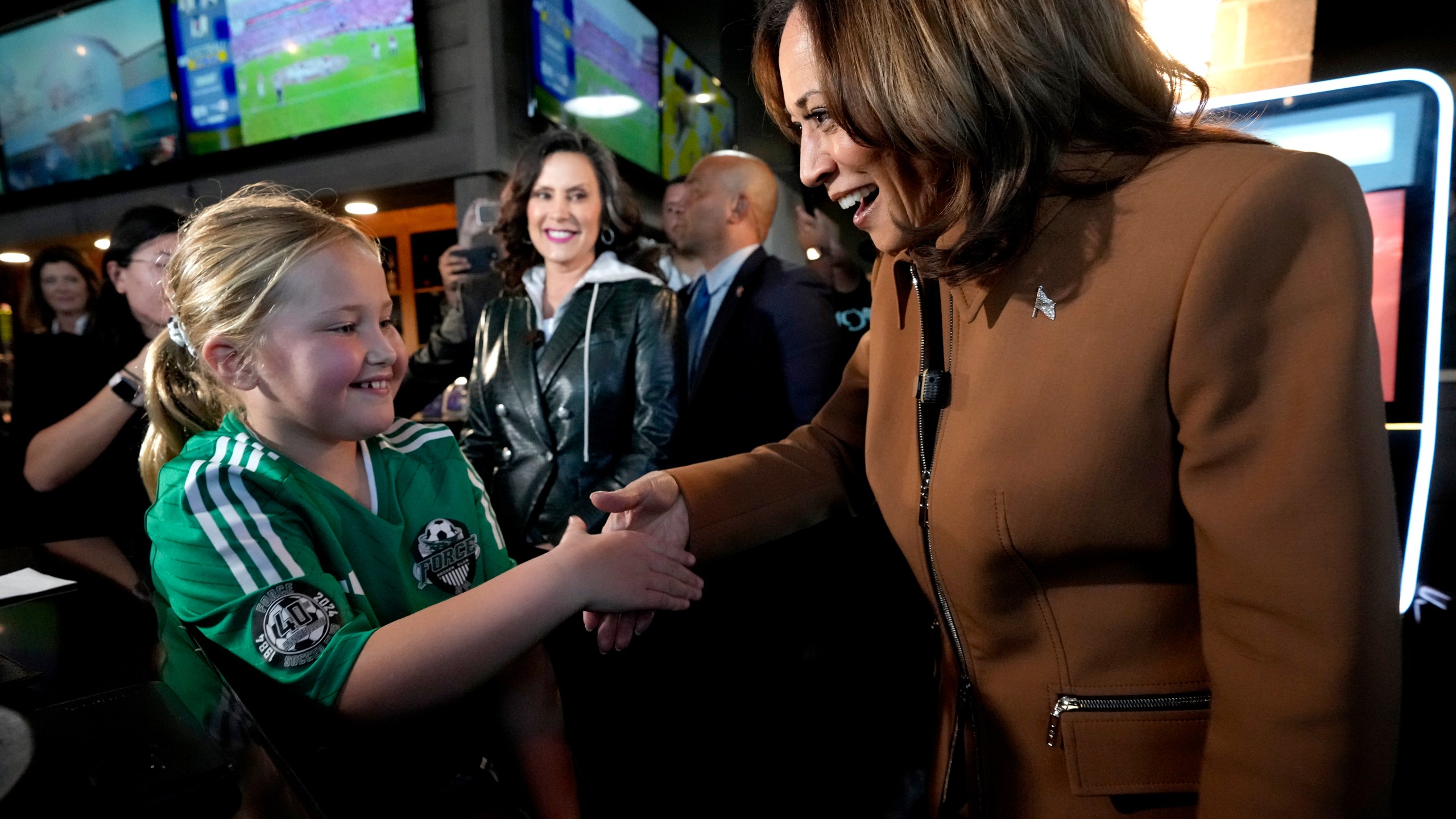 Democratic presidential nominee Vice President Kamala Harris, from right, and Michigan Gov. Gretchen Whitmer greet a young customer at the Trak Houz Bar & Grill after a campaign rally in Kalamazoo, Mich. (AP Photo/Jacquelyn Martin)