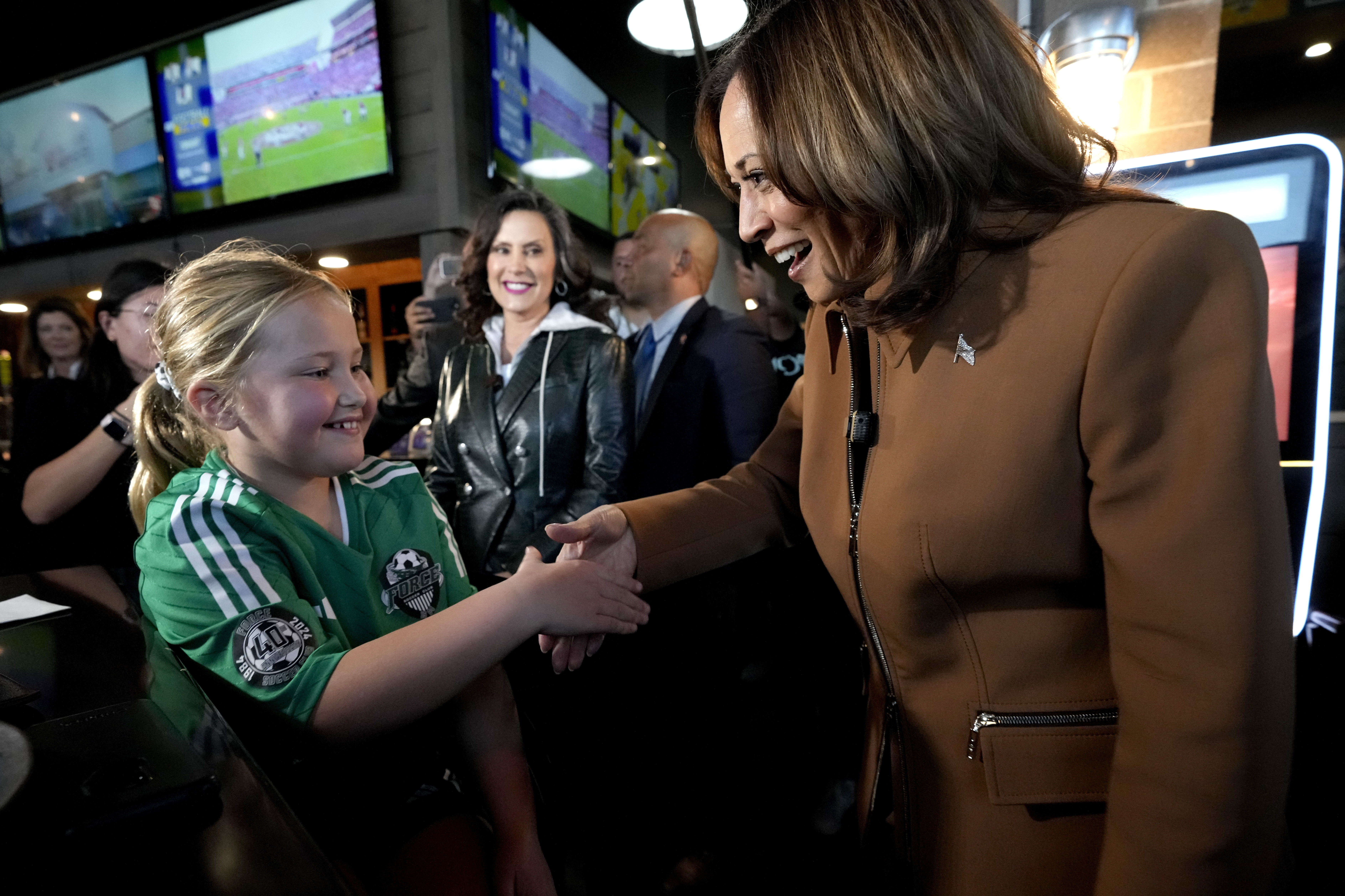 Democratic presidential nominee Vice President Kamala Harris, from right, and Michigan Gov. Gretchen Whitmer greet a young customer at the Trak Houz Bar & Grill after a campaign rally in Kalamazoo, Mich. (AP Photo/Jacquelyn Martin)