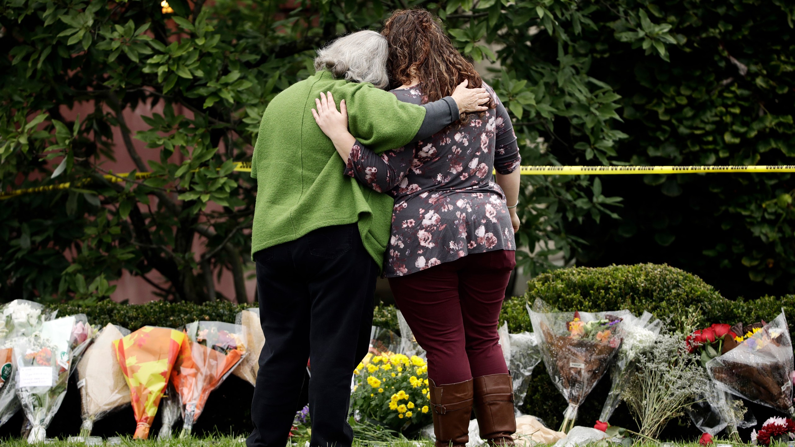 FILE - Two people support each other in front of flowers at a makeshift memorial at the Tree of Life Synagogue in Pittsburgh, Sunday, Oct. 28, 2018. (AP Photo/Matt Rourke, File)