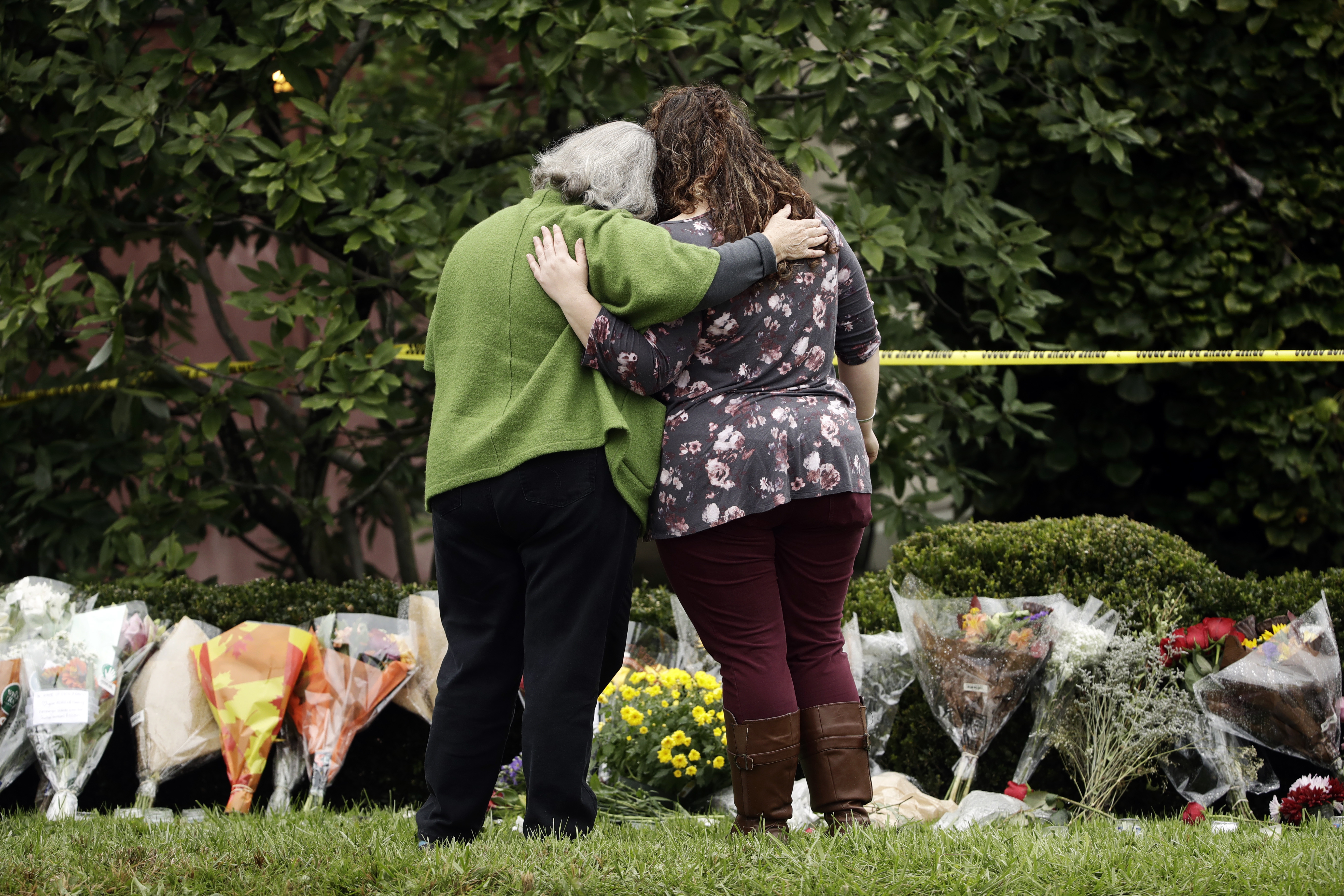 FILE - Two people support each other in front of flowers at a makeshift memorial at the Tree of Life Synagogue in Pittsburgh, Sunday, Oct. 28, 2018. (AP Photo/Matt Rourke, File)