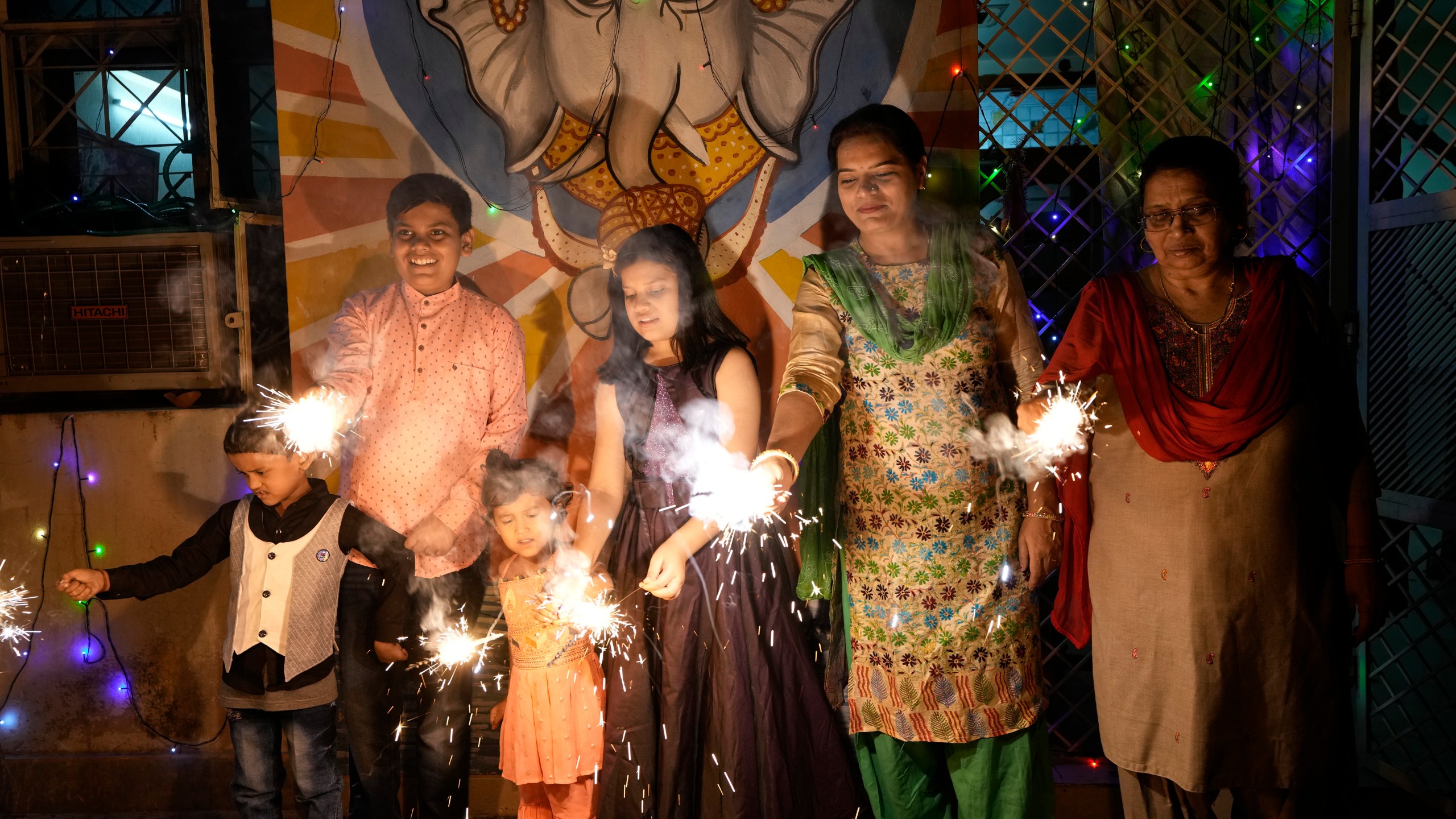 FILE- An Indian family lights firecrackers to celebrate Diwali, the Hindu festival of lights, in Prayagraj, in the northern state of Uttar Pradesh, India, Oct. 24, 2022. (AP Photo/Rajesh Kumar Singh, File)