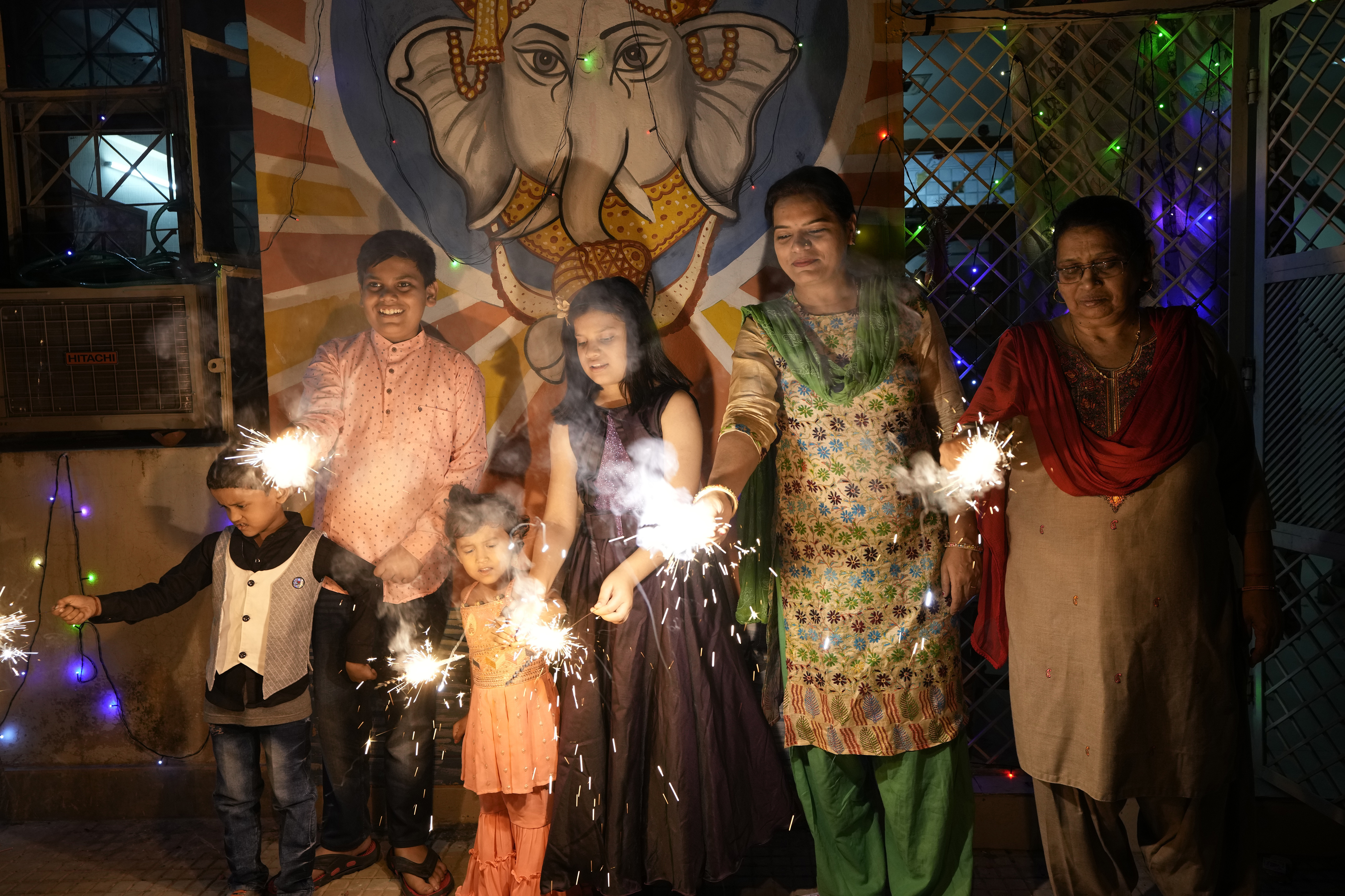 FILE- An Indian family lights firecrackers to celebrate Diwali, the Hindu festival of lights, in Prayagraj, in the northern state of Uttar Pradesh, India, Oct. 24, 2022. (AP Photo/Rajesh Kumar Singh, File)