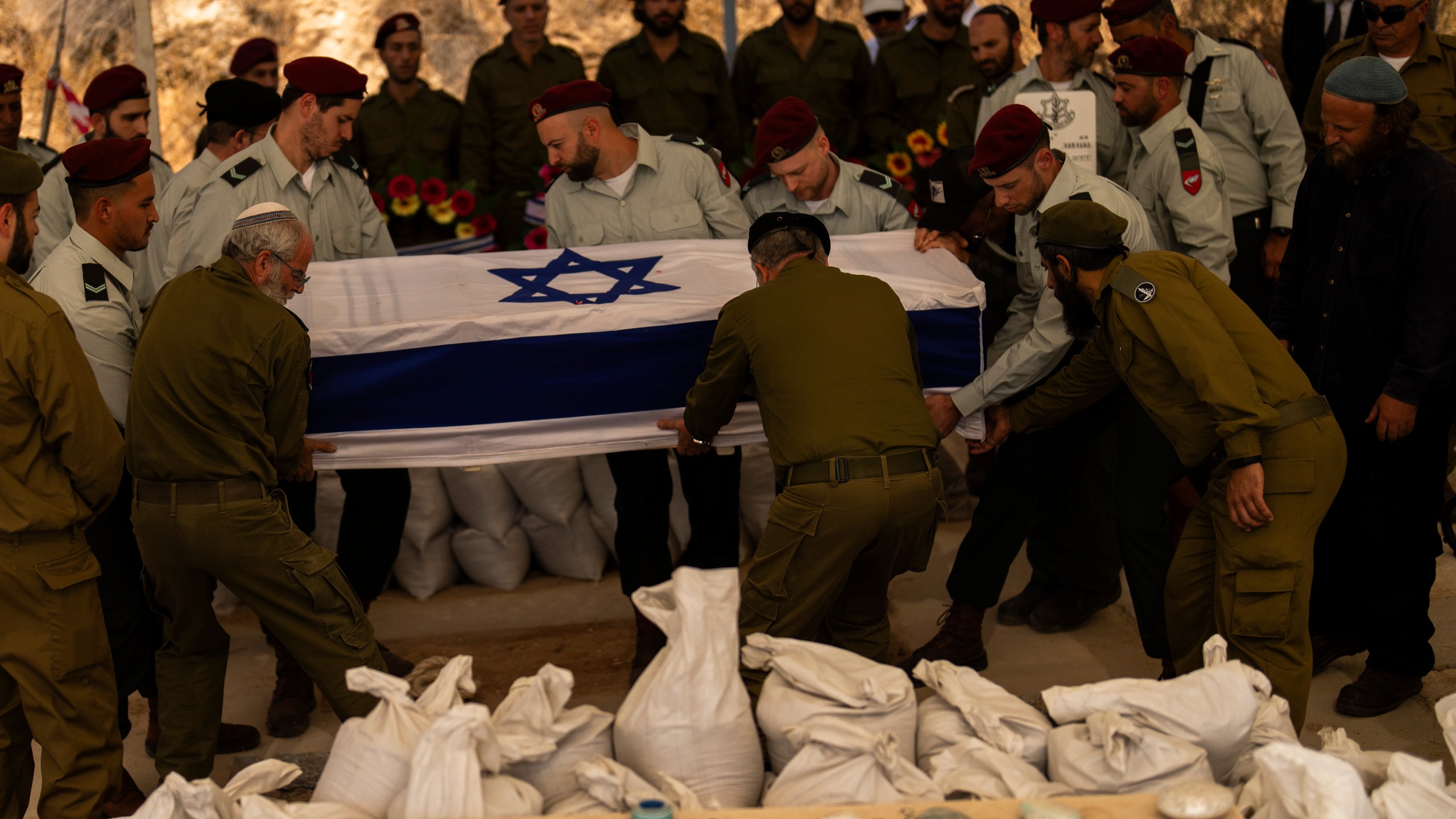 Israeli soldiers lower into the grave the flagged-covered coffin of reservist Yedidia Bloch, 31, during his funeral at Mevo Horon settlement, West Bank, Wednesday, Oct. 30, 2024. Bloch died on Tuesday 29 after he was injured in Lebanon. (AP Photo/Francisco Seco)