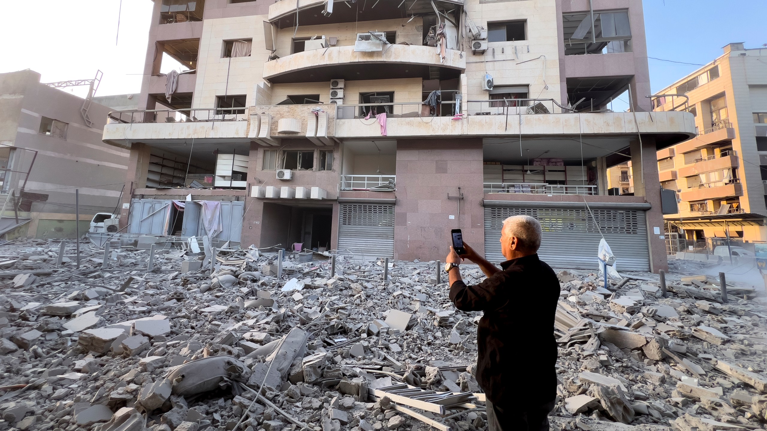 A man takes pictures by his mobile phone of a destroyed building hit by an Israeli airstrike on Dahiyeh, in the southern suburb of Beirut, Lebanon, early Friday, Nov. 1, 2024. (AP Photo/Hussein Malla)