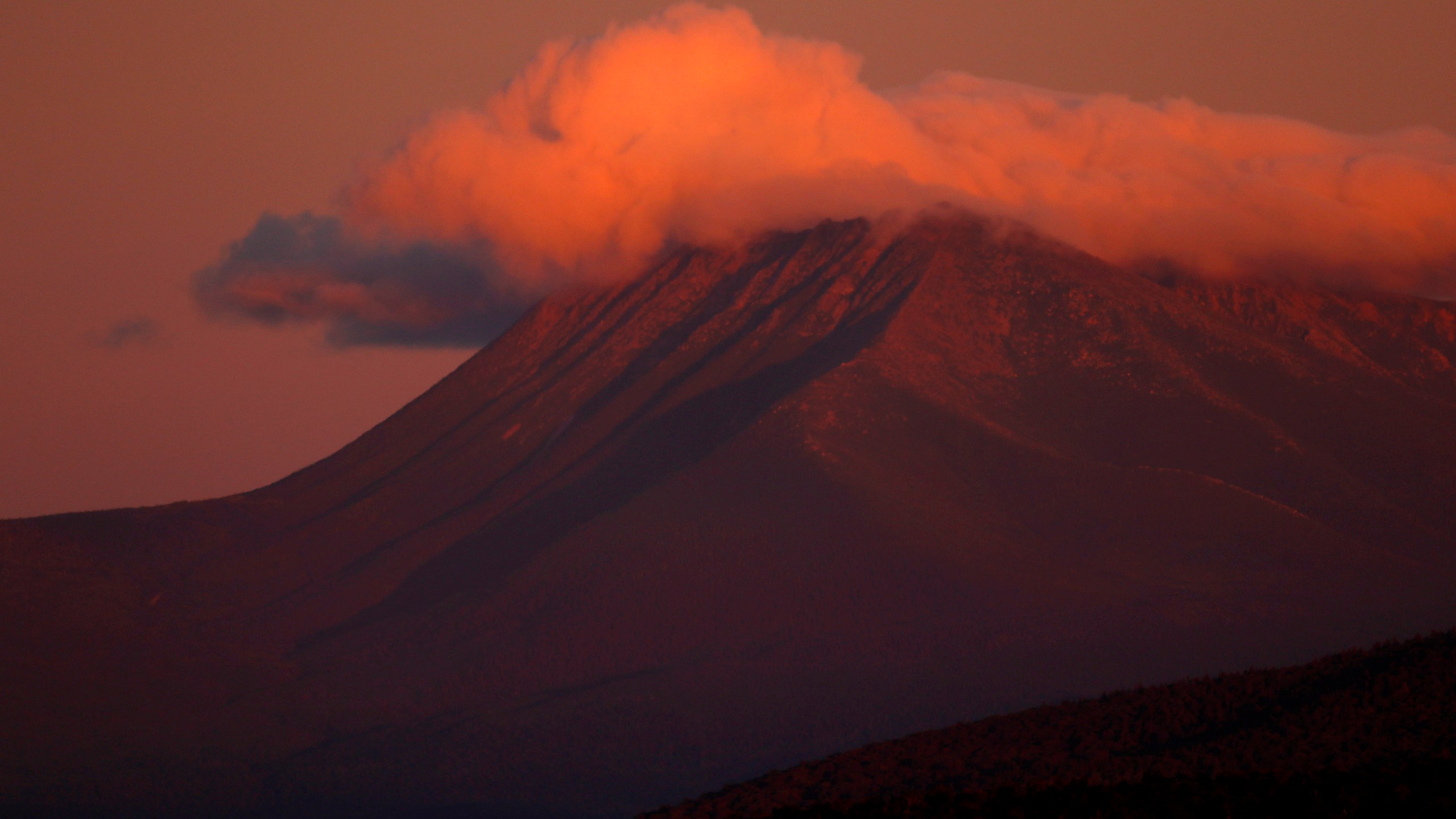 FILE - In this Aug. 7, 2017, file photo, the first rays of sunlight color the clouds over Mount Katahdin in this view from Patten, Maine. (AP Photo/Robert F. Bukaty, File)