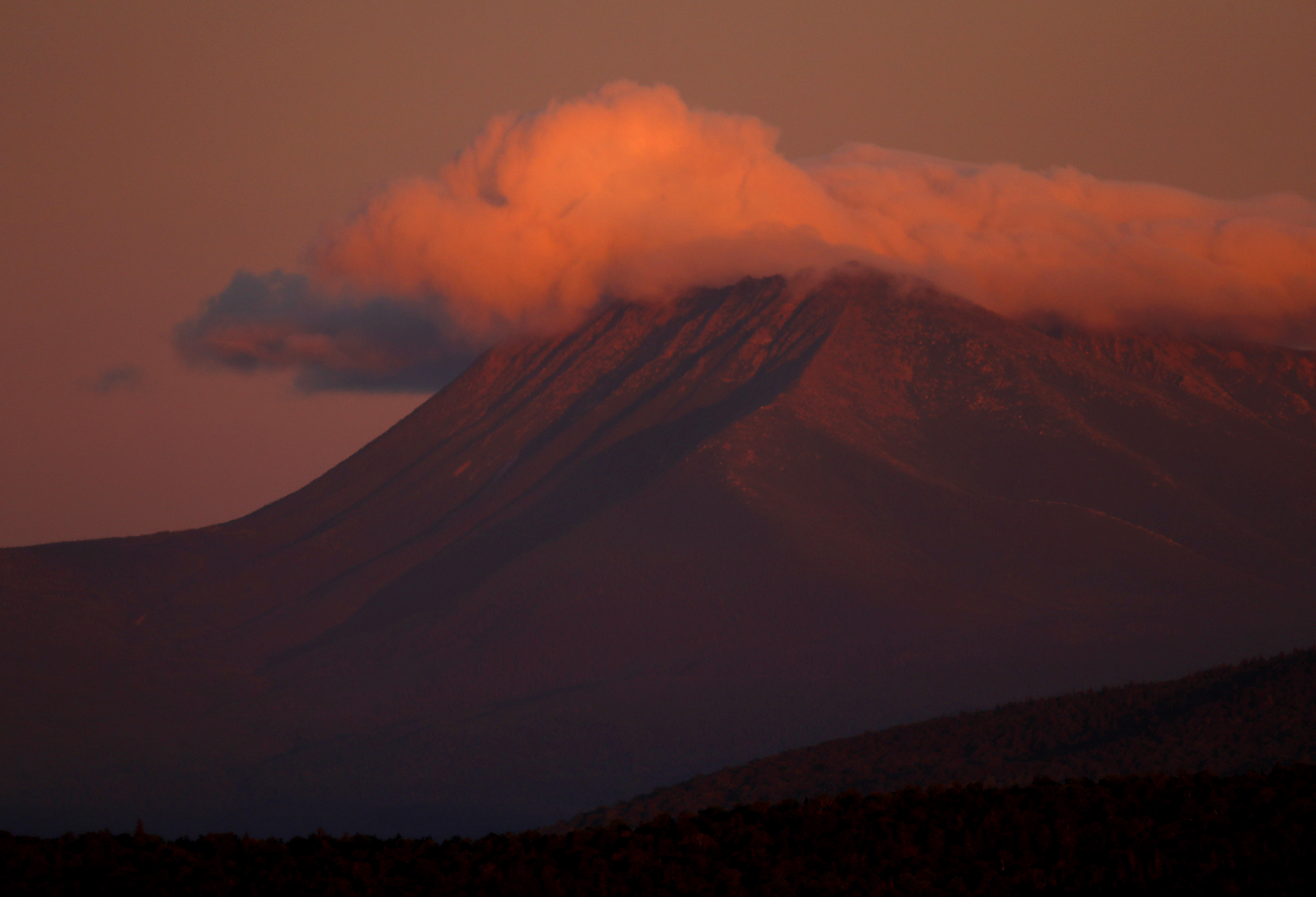 FILE - In this Aug. 7, 2017, file photo, the first rays of sunlight color the clouds over Mount Katahdin in this view from Patten, Maine. (AP Photo/Robert F. Bukaty, File)