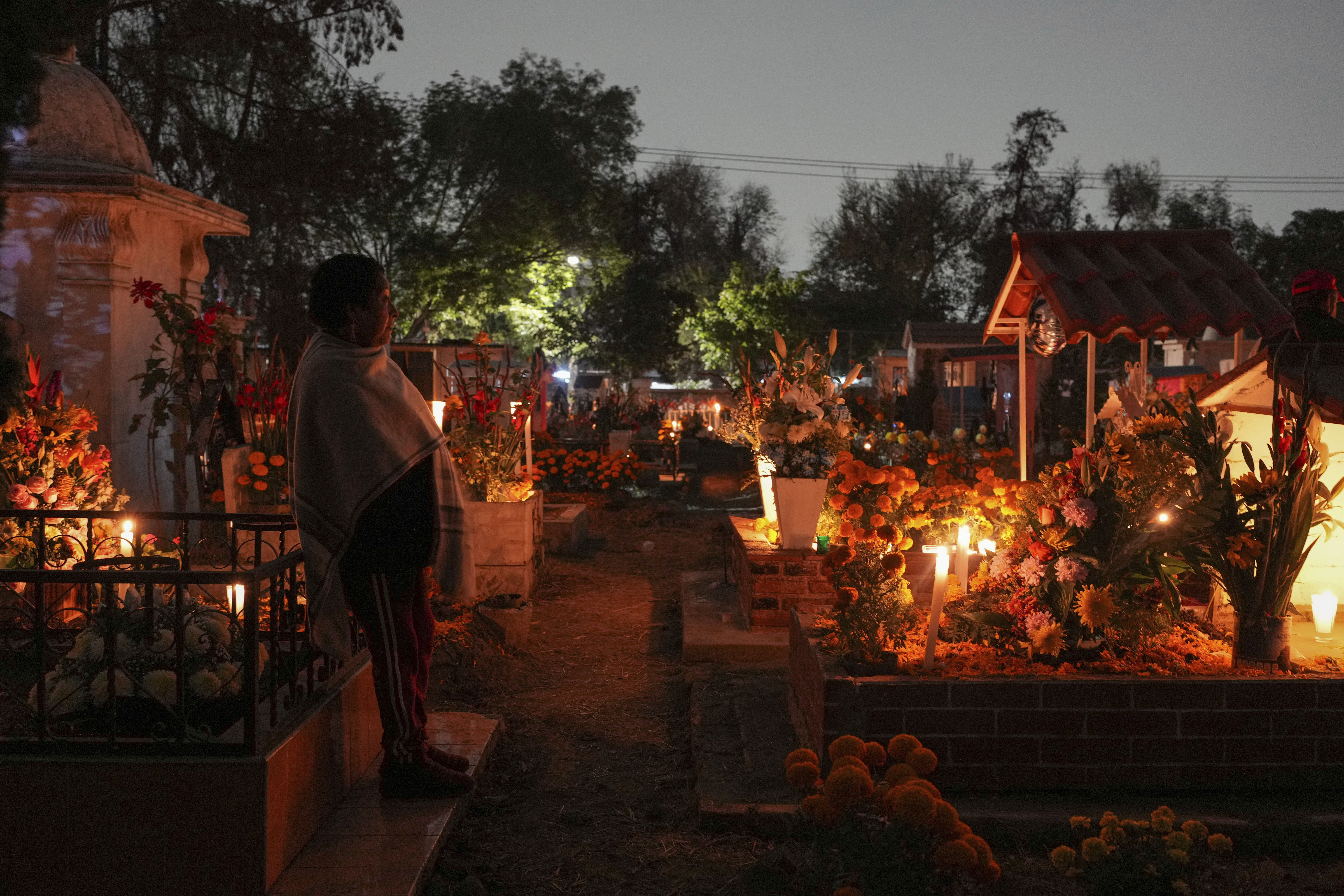 A woman stands at a tomb of a dearly departed, celebrating Day of the Dead, at the San Gregorio Atlapulco cemetery on the outskirts of Mexico City, Friday, Nov. 1, 2024. (AP Photo/Moises Castillo)