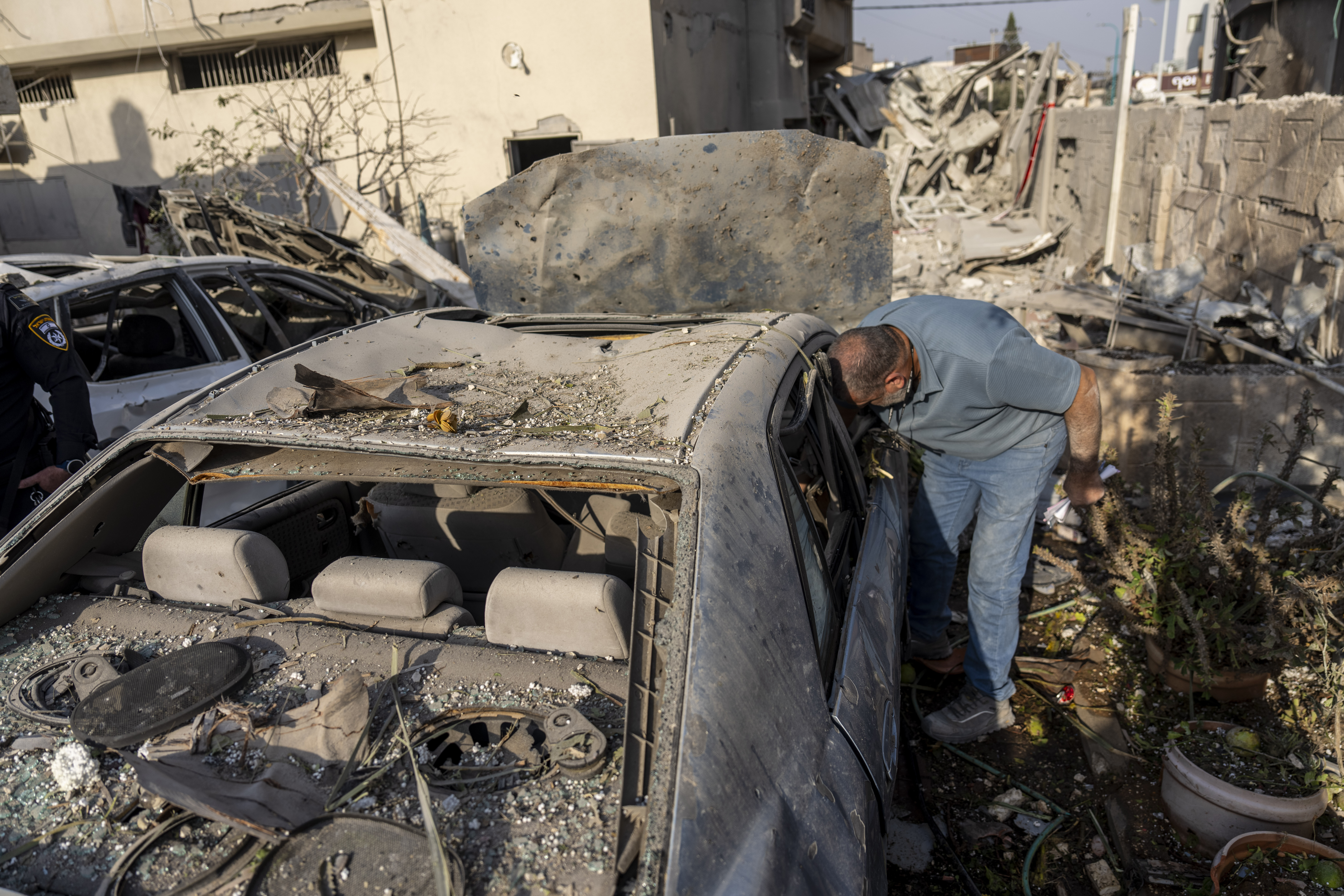 A man surveys damage to his car after projectiles fired from Lebanon hit a home in Tira, central Israel, Saturday, Nov. 2, 2024. (AP Photo/Ariel Schalit)