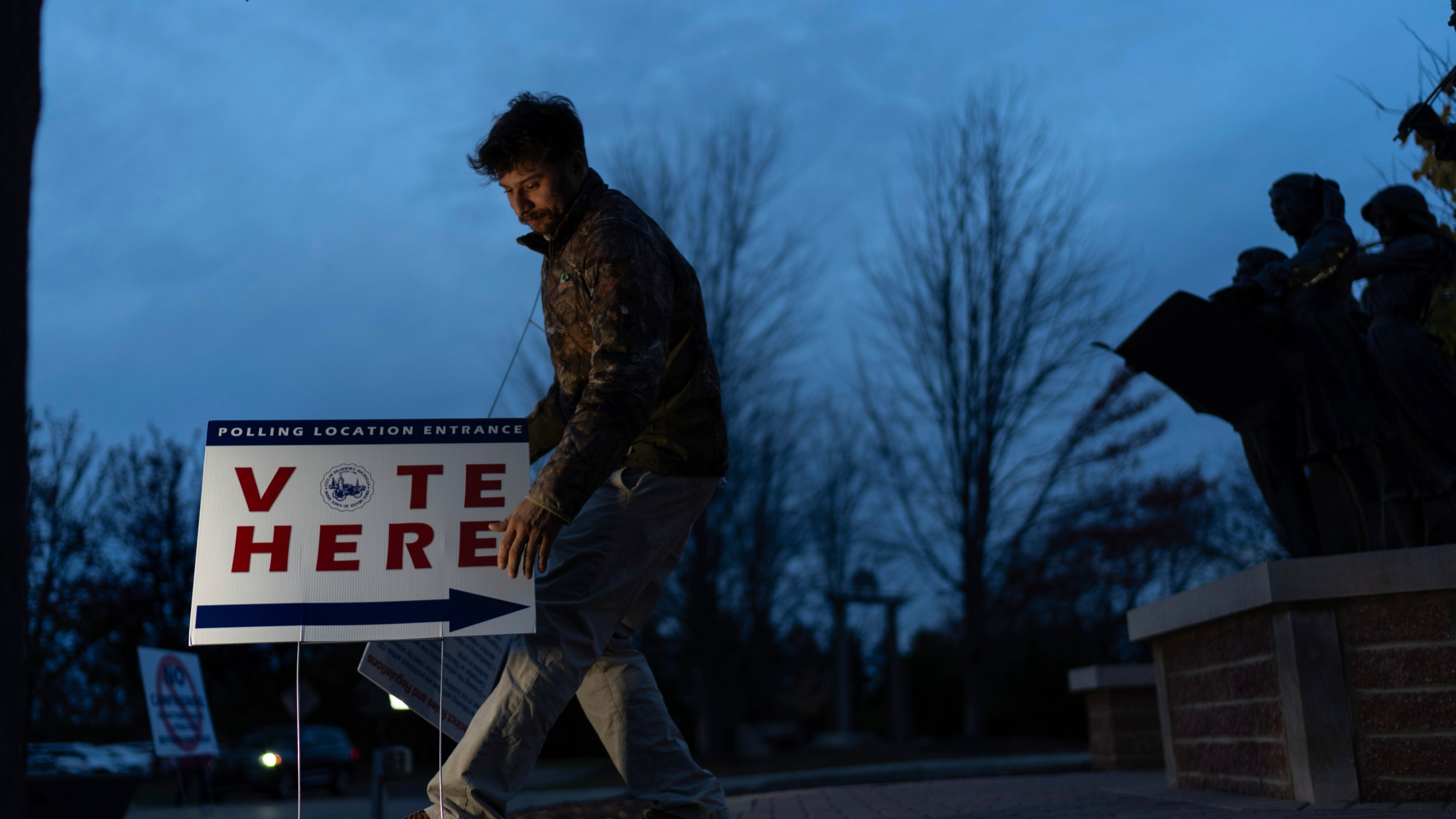 Election official Anthony Salinger removes a sign outside the polling site at Ford Community and Performing Arts Center as early in-person voting comes to an end, Sunday, Nov. 3, 2024, in Dearborn, Mich. (AP Photo/David Goldman)