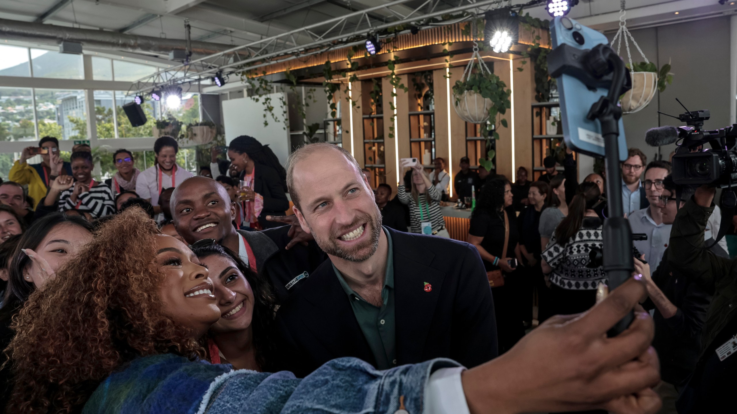 Nomzamo Mbatha, left, the host of Earthshot Week, takes a selfie with Britain's Prince William and a group of young people at the Earthshot Prize Climate Leaders Youth Programme at Rooftop on Bree in Cape Town, South Africa, Monday Nov. 4, 2024. (Gianluigi Guercia/Pool Photo via AP)