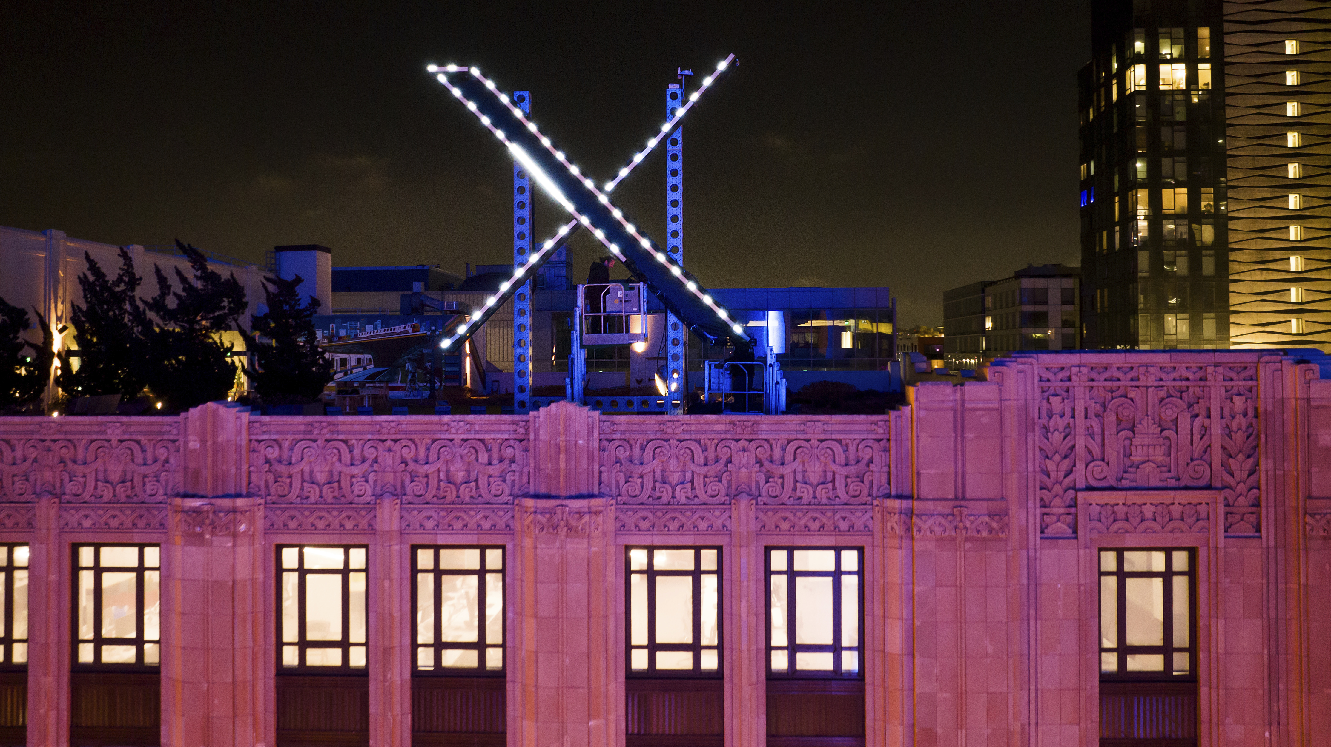 FILE - Workers install lighting on an "X" sign atop the company headquarters, formerly known as Twitter, in downtown San Francisco, July 28, 2023. (AP Photo/Noah Berger, File)