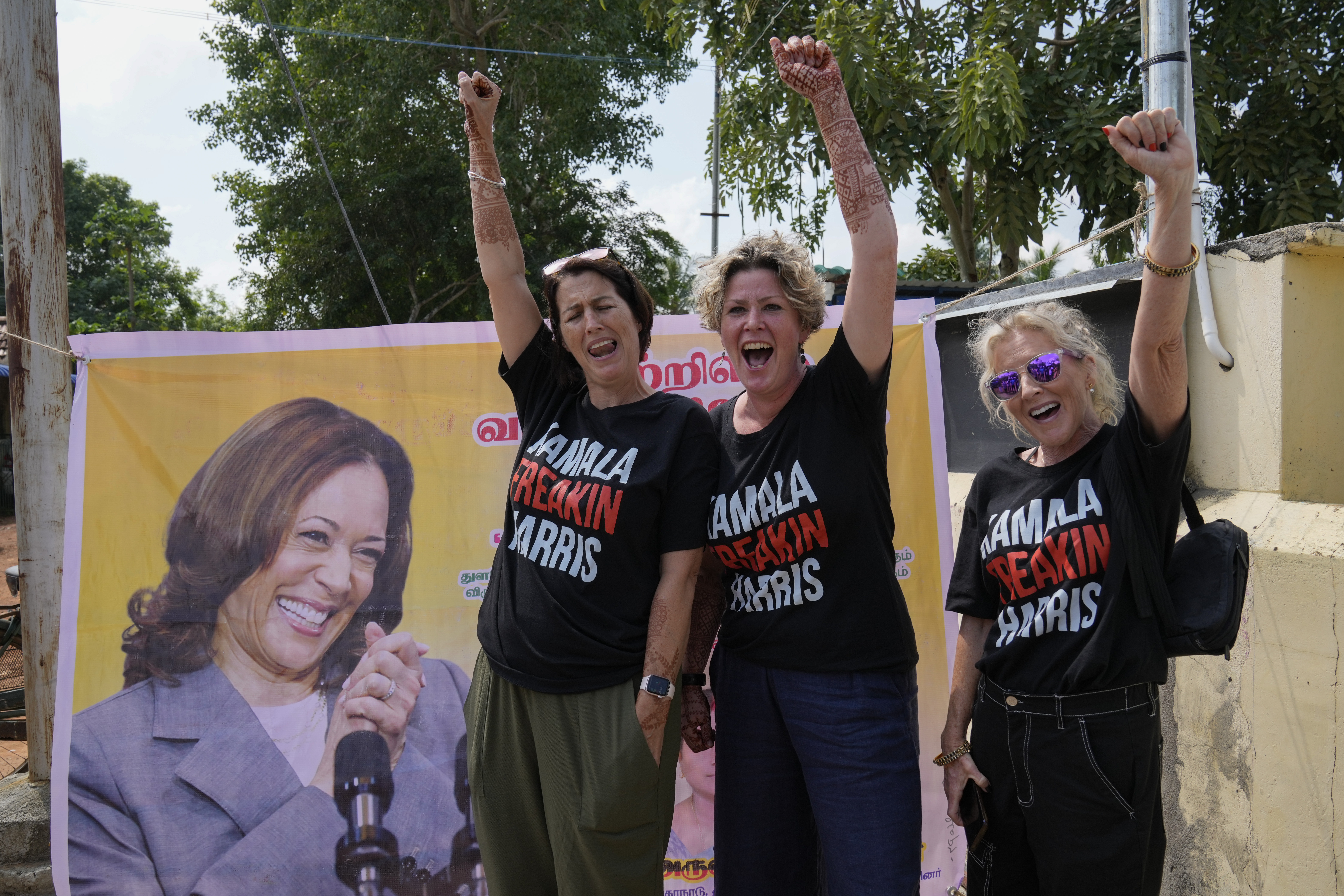 From left, Fiana Jones of United Kingdom, Devony Evans and Sajron Silalenka of United States wearing tees and cheer for Democratic presidential nominee Vice President Kamala Harris outside a temple in Thulasendrapuram, the ancestral village of Harris, in Tamil Nadu state, India, Tuesday, Nov. 5, 2024. (AP Photo/Aijaz Rahi)