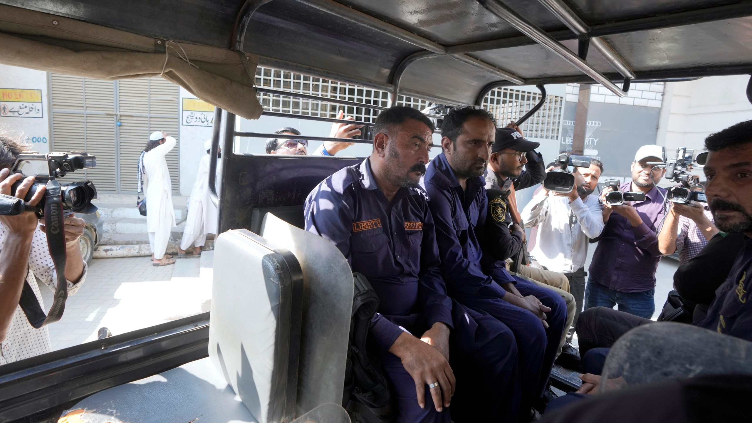 Police officers transport security guards, center, who shot and wounded at least a few Chinese nationals working in a textile mill, in a vehicle as they take them into custody, in Karachi, Pakistan, Tuesday, Nov. 5, 2024. (AP Photo/Fareed Khan)