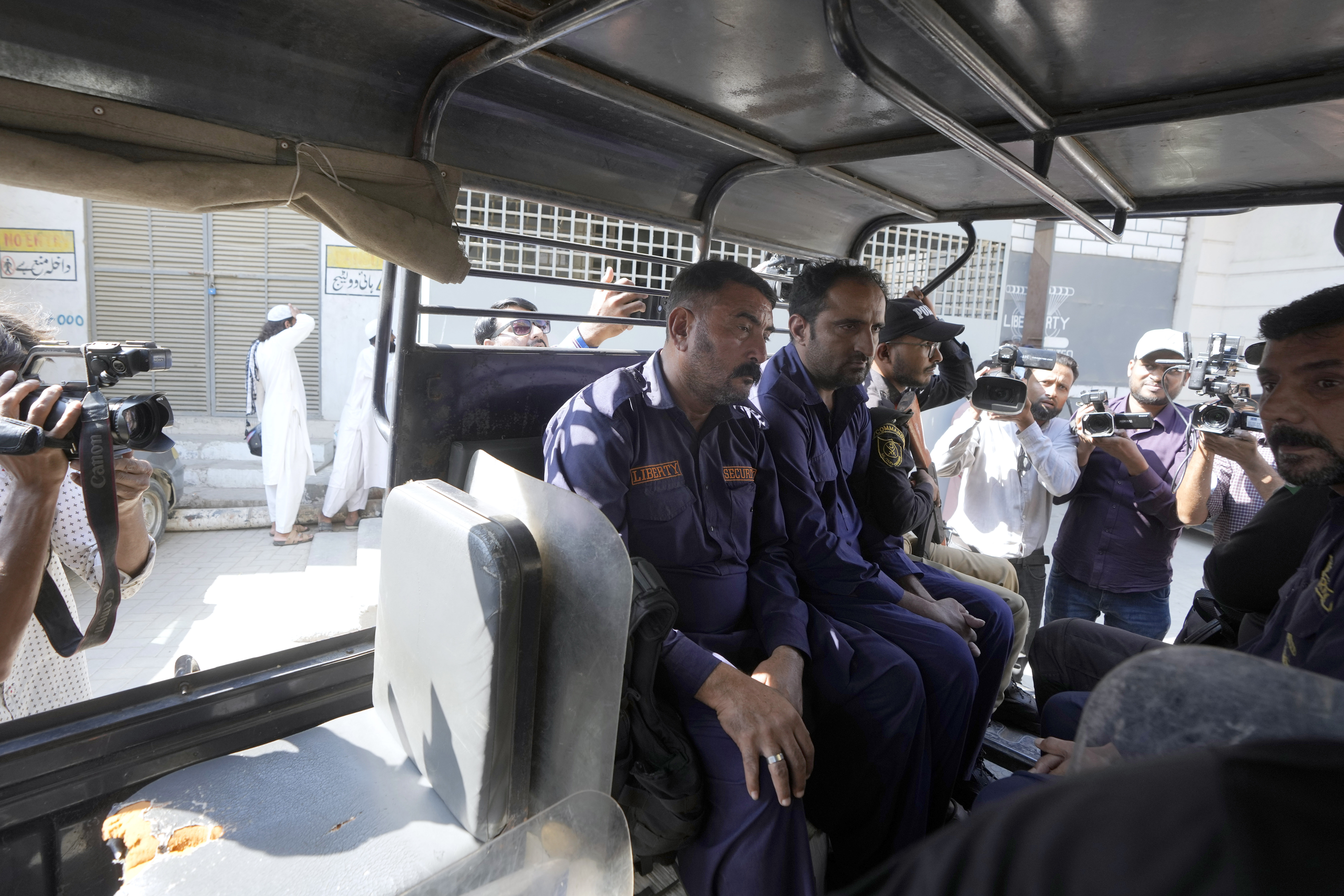 Police officers transport security guards, center, who shot and wounded at least a few Chinese nationals working in a textile mill, in a vehicle as they take them into custody, in Karachi, Pakistan, Tuesday, Nov. 5, 2024. (AP Photo/Fareed Khan)