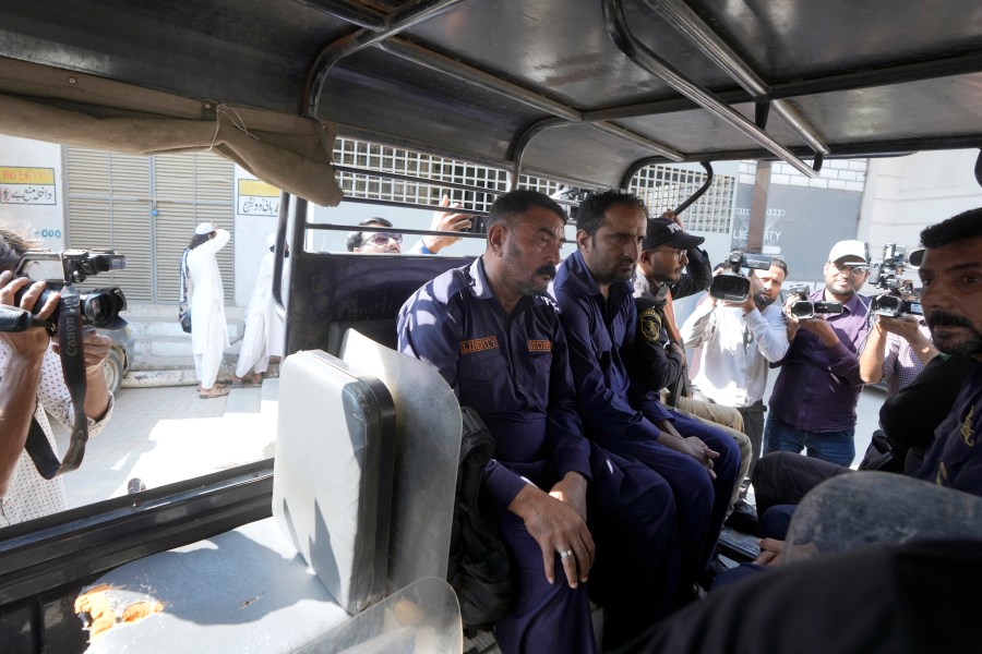 Police officers transport security guards, center, who shot and wounded at least a few Chinese nationals working in a textile mill, in a vehicle as they take them into custody, in Karachi, Pakistan, Tuesday, Nov. 5, 2024. (AP Photo/Fareed Khan)