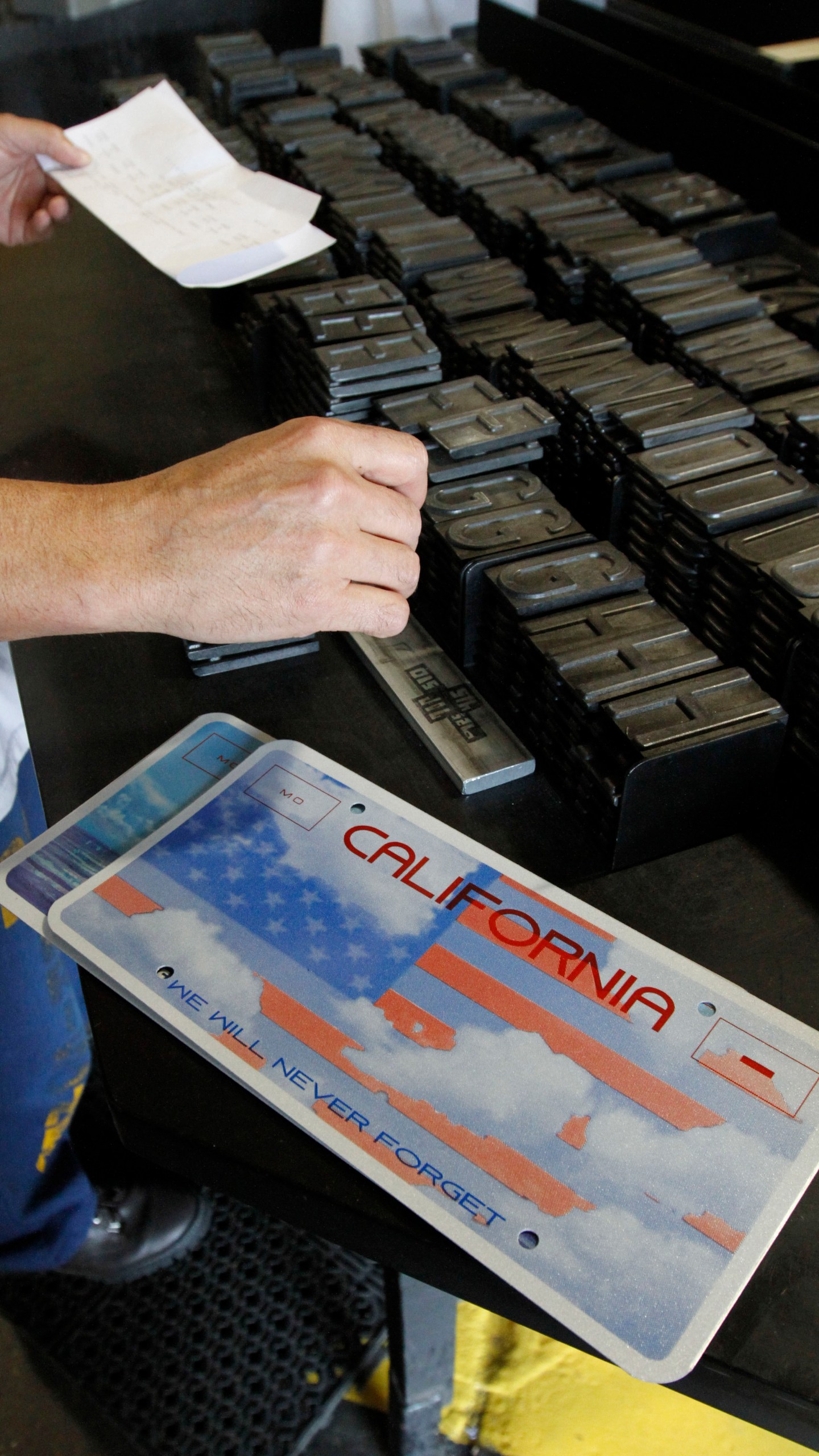 FILE - An inmate selects the letters and numbers to be used to make a specialty license plate by Prison Industries at Folsom State Prison, May 15, 2012, in Folsom, Calif.(AP Photo/Rich Pedroncelli, File)