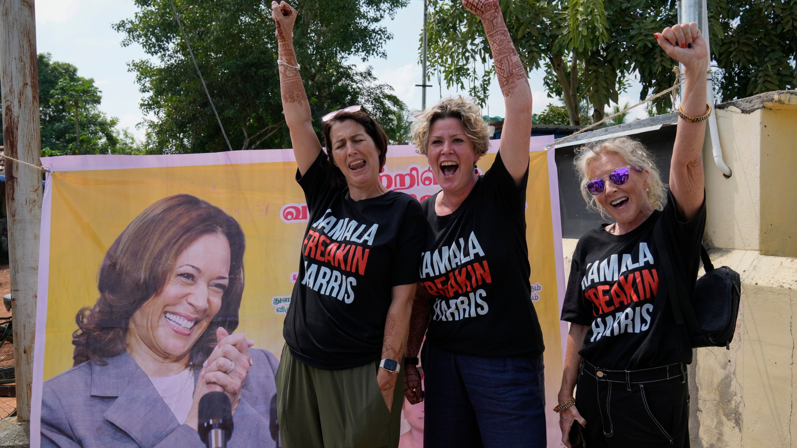 From left, Fiana Jones of United Kingdom, Devony Evans and Sajron Silalenka of United States wearing tees and cheer for Democratic presidential nominee Vice President Kamala Harris outside a temple in Thulasendrapuram, the ancestral village of Harris, in Tamil Nadu state, India, Tuesday, Nov. 5, 2024. (AP Photo/Aijaz Rahi)