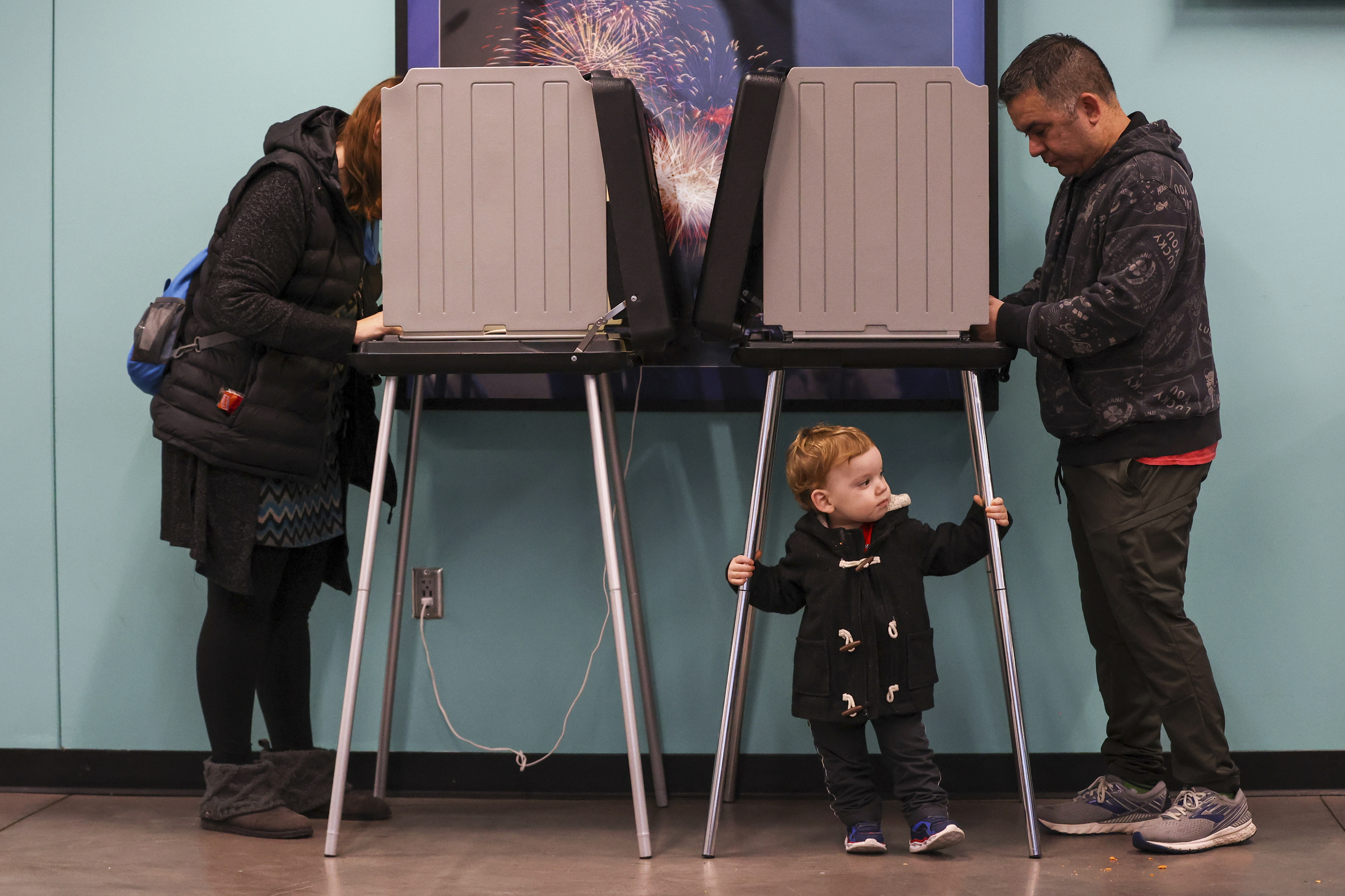 Oliver Barragan, 2, center, waits for his mother, Richelle Barragan, left, as she votes on Election Day at Werner Park, Tuesday, Nov. 5, 2024, in Papillion, Neb. (Liz Rymarev/Omaha World-Herald via AP)