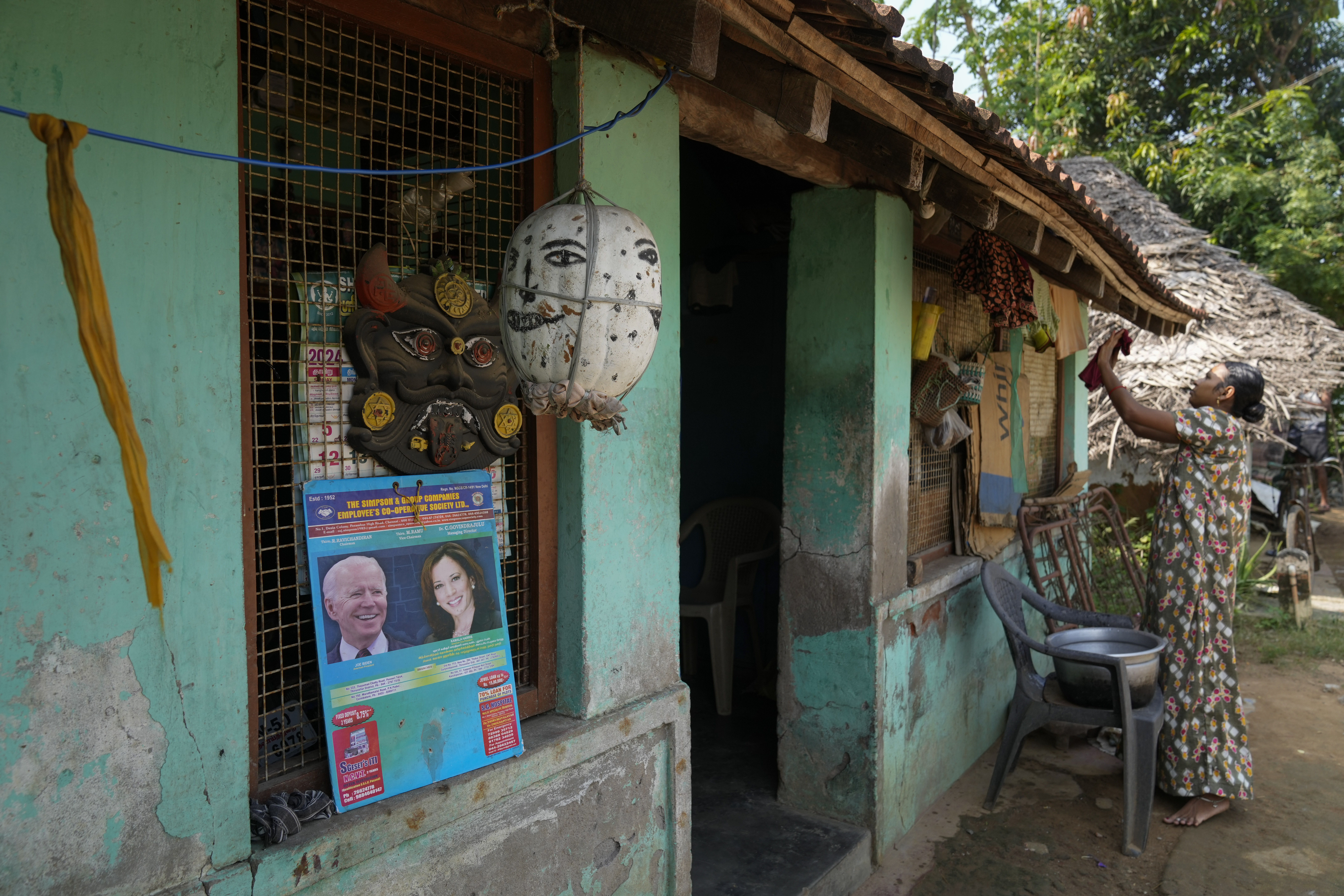 A calendar featuring photographs of U.S. President Joe Biden and Democratic presidential nominee Vice President Kamala Harris is placed on a window as a villager puts clothes to dry outside her house in Thulasendrapuram, the ancestral village of Harris, in Tamil Nadu state, India, Wednesday, Nov. 6, 2024. (AP Photo/Aijaz Rahi)