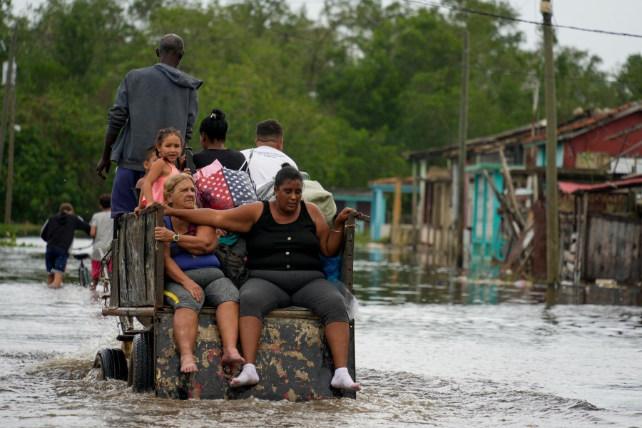 Residents ride through a flooded street on a horse-drawn cart after Hurricane Rafael passed through Batano, Cuba, Thursday, Nov. 7, 2024. (AP Photo/Ramon Espinosa)