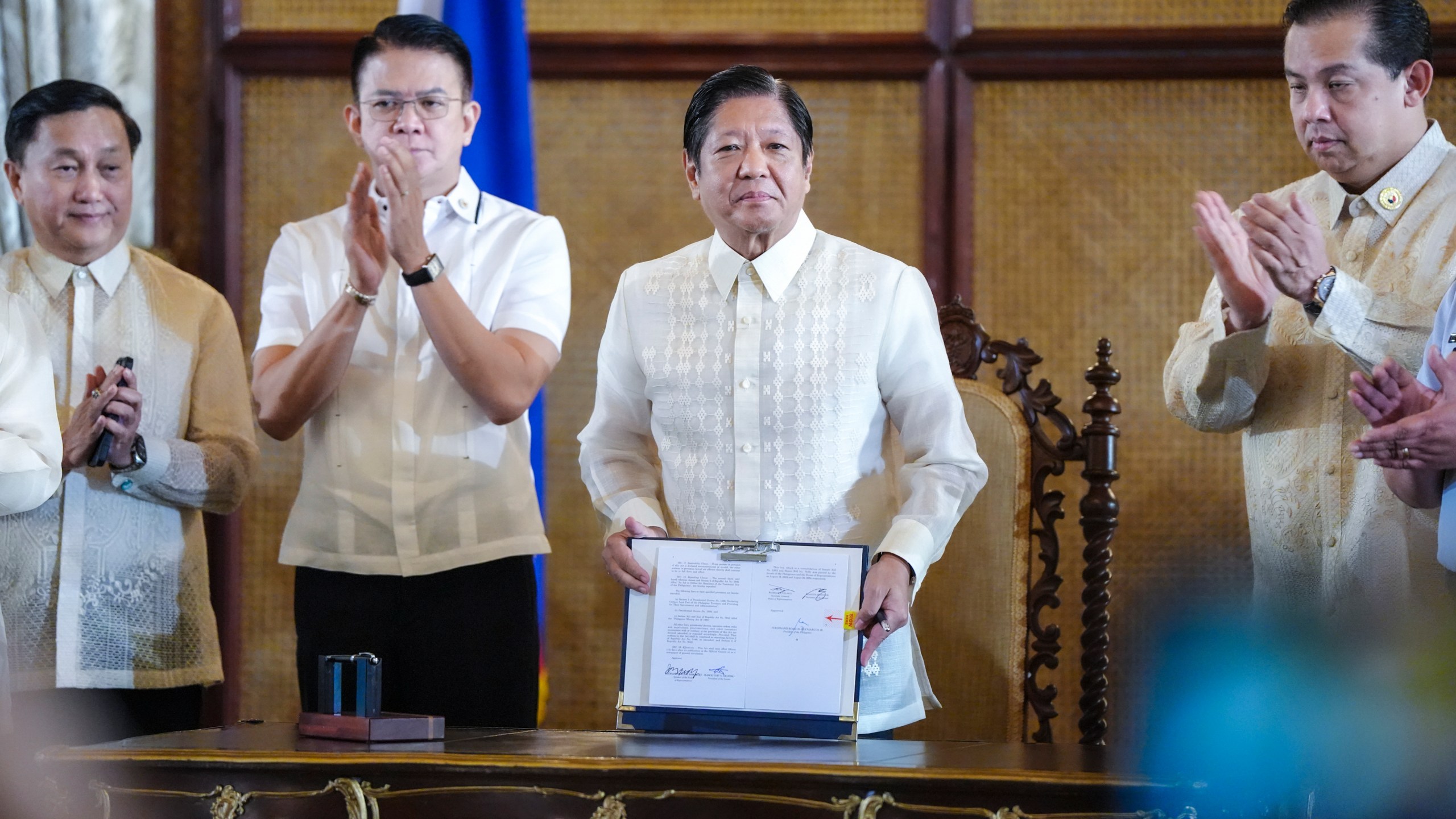 In this photo provided by the Malacanang Presidential Communications Office, Philippine President Ferdinand Marcos Jr., second from right, shows a document beside Senate President Francis Escudero, second from left, and House Speaker Martin Romualdez during the ceremonial signing of the Philippine Maritime Zones and Philippine Archipelagic Sea Lanes Act at the Malacanang presidential palace in Manila, Philippines on Friday, Nov. 8, 2024. (Malacanang Presidential Communications Office via AP)