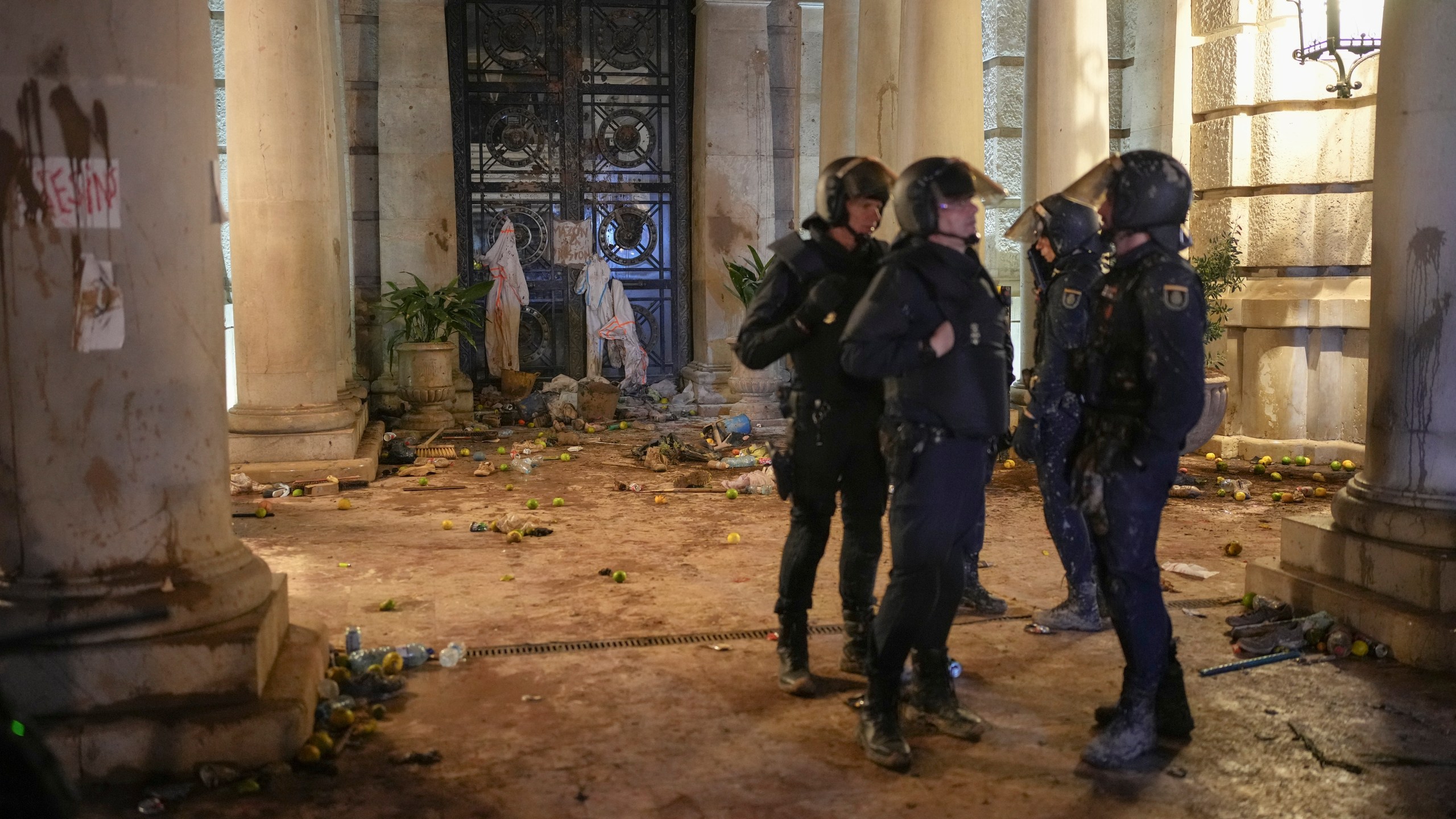 Riot police stand next to a government building littered by some demonstrators during minor clashes after a peaceful protest organized by social and civic groups, denouncing the handling of recent flooding under the slogan "Mazon, Resign," aimed at the president of the regional government Carlos Mazon, in Valencia, Spain, Saturday, Nov. 9, 2024. (AP Photo/Emilio Morenatti)