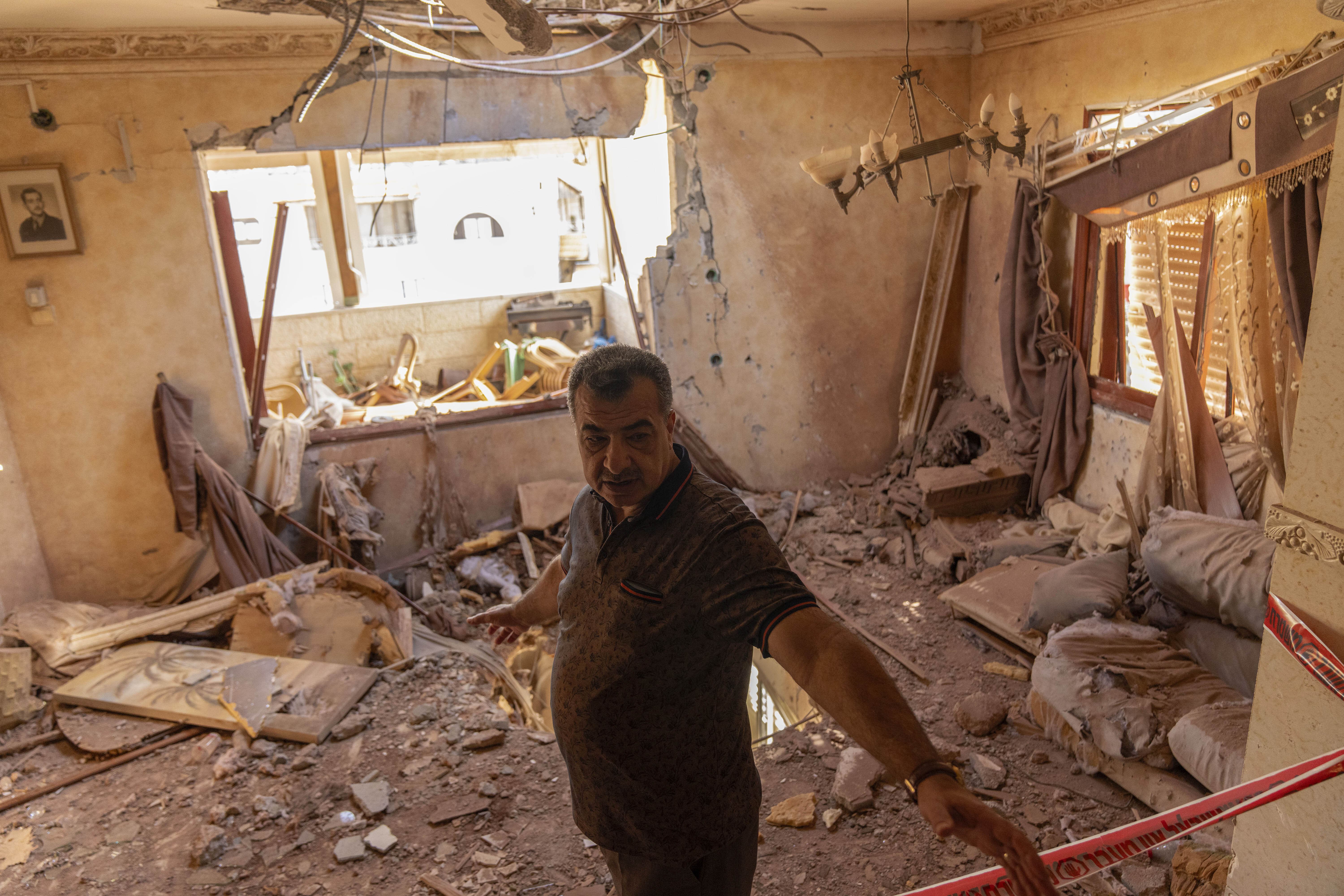 A local resident stands next to debris inside his house after it was struck by projectiles fired from Lebanon in Kfar Yasif, north west Israel, Saturday, Nov. 9, 2024. (AP Photo/Francisco Seco)