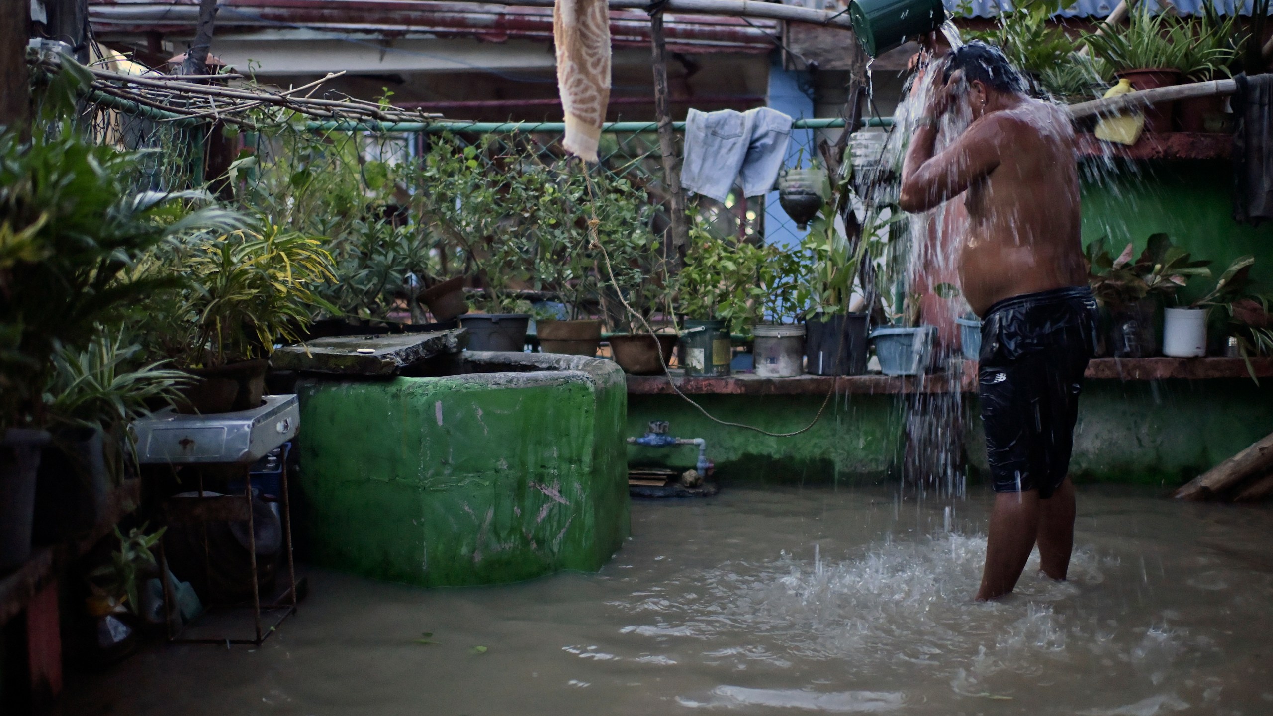 A resident takes a bath in a flooded village after Typhoon Yinxing, locally called Marce, blew past Buguey town, Cagayan province, northern Philippines on Friday Nov. 8, 2024. (AP Photo/Noel Celis)