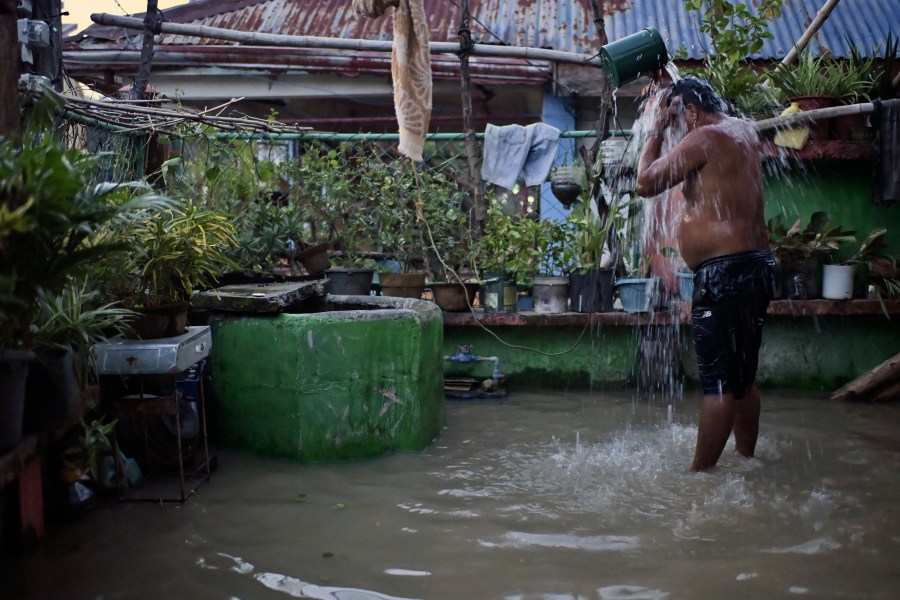 A resident takes a bath in a flooded village after Typhoon Yinxing, locally called Marce, blew past Buguey town, Cagayan province, northern Philippines on Friday Nov. 8, 2024. (AP Photo/Noel Celis)