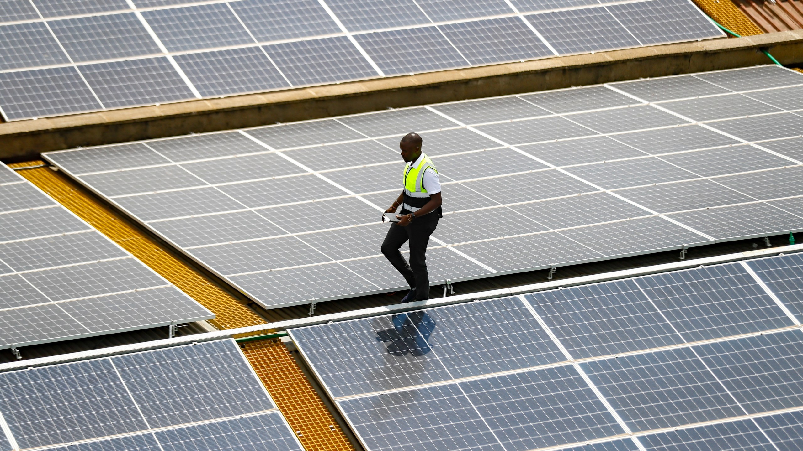 FILE - Mark Munyua, CP solar's technician, examines solar panels on the roof of a company in Nairobi, Kenya, Sept. 1, 2023. (AP Photo/Brian Inganga, File)