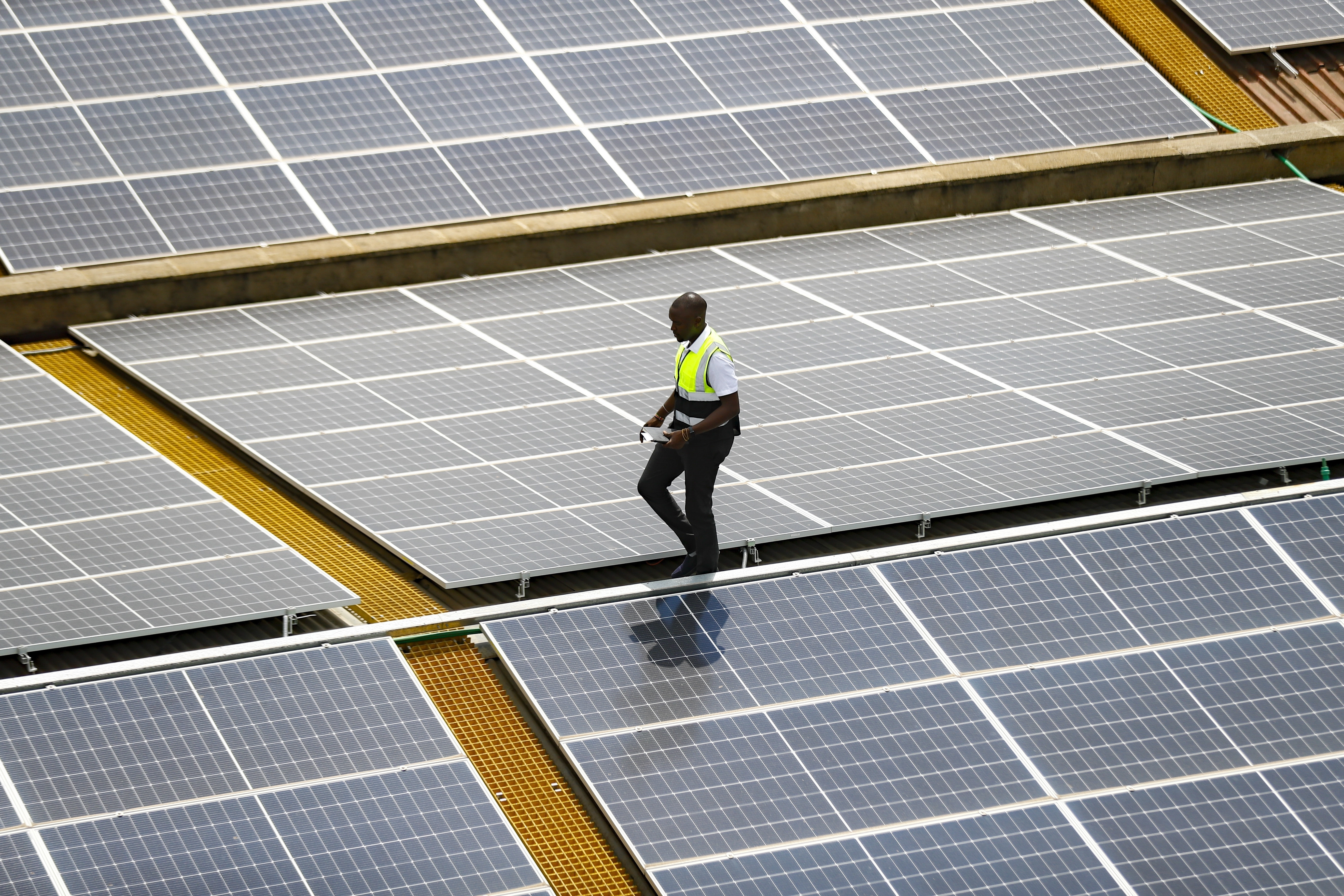 FILE - Mark Munyua, CP solar's technician, examines solar panels on the roof of a company in Nairobi, Kenya, Sept. 1, 2023. (AP Photo/Brian Inganga, File)