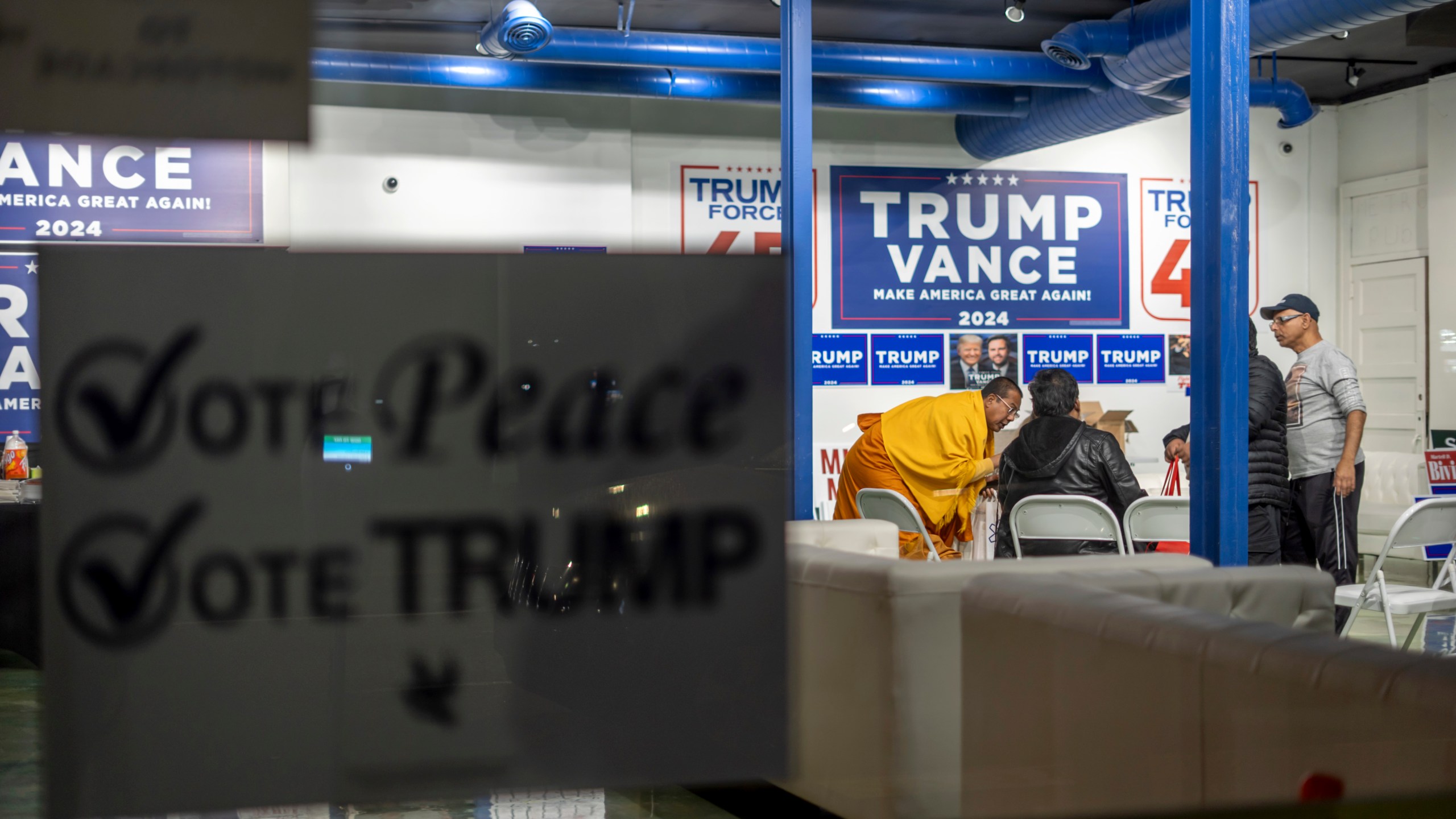 A sign hangs in the window as volunteers meet in the campaign office for Republican presidential nominee former President Donald Trump, Monday, Nov. 4, 2024, in Hamtramck, Mich. (AP Photo/David Goldman)