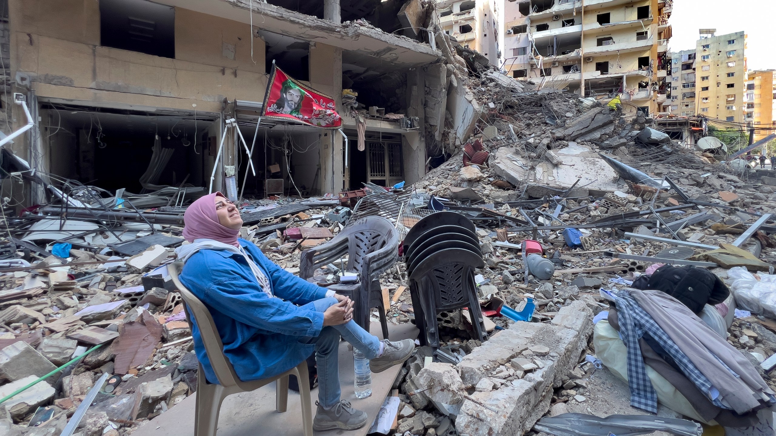 A woman sits on the rubble as she looks to a building destroyed by an Israeli airstrike in Dahiyeh, in the southern suburb of Beirut, Lebanon, Monday, Nov. 11, 2024. (AP Photo/Hussein Malla)