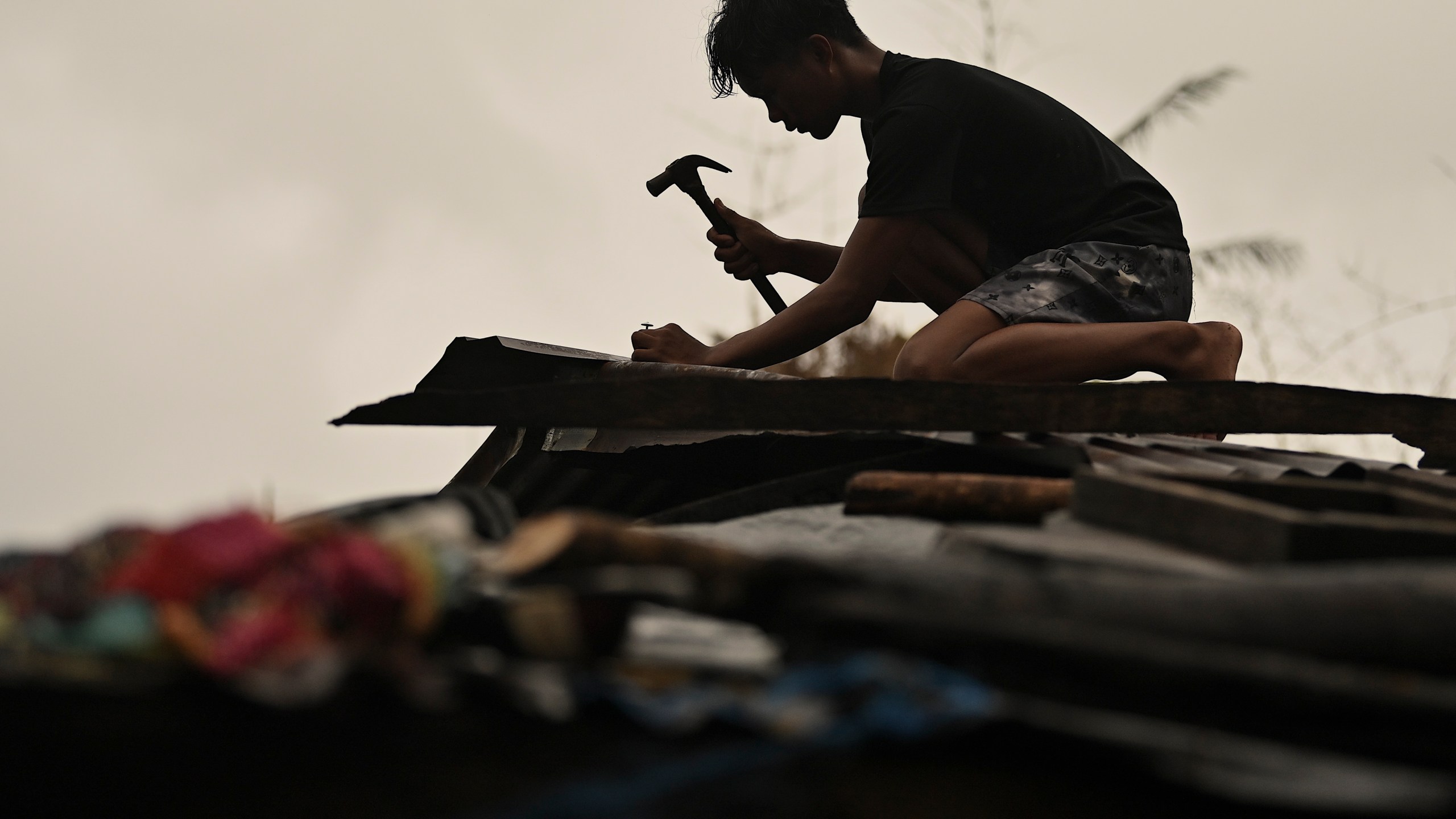 A resident reinforces his roof in Santa Ana, Cagayan Province, northern Philippines as they anticipate Typhoon Usagi to hit their area Thursday, Nov. 14, 2024. (AP Photo/Noel Celis)