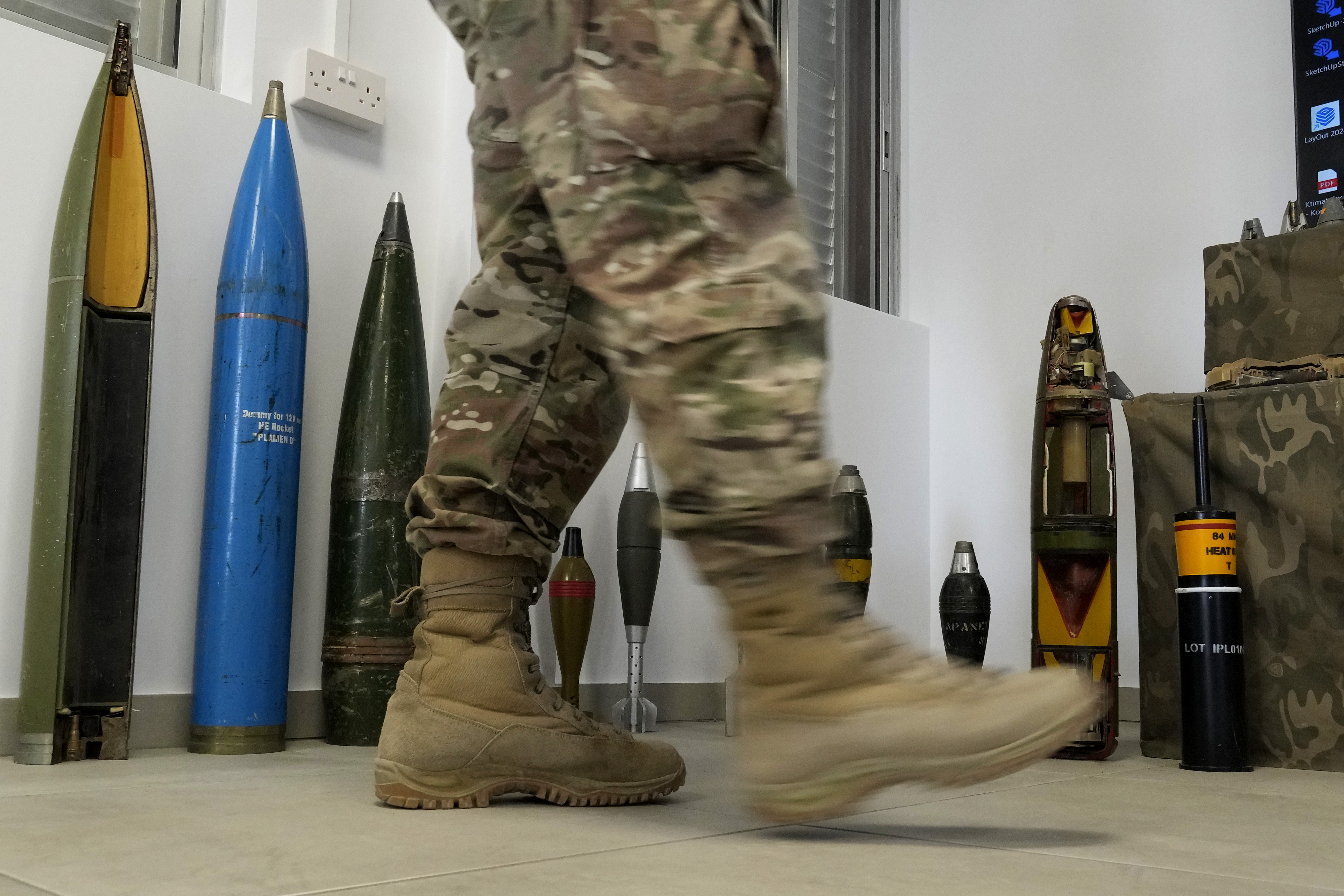 A Cypriot National Guardsman walks in front of a display of inert rockets, artillery shells and other munitions as part of a training course of Ukrainian personnel in the disposal of landmines and other explosive ordnance in Cyprus, at an army base in Nicosia, Thursday, Nov. 14, 2024. (AP Photo/Petros Karadjias)