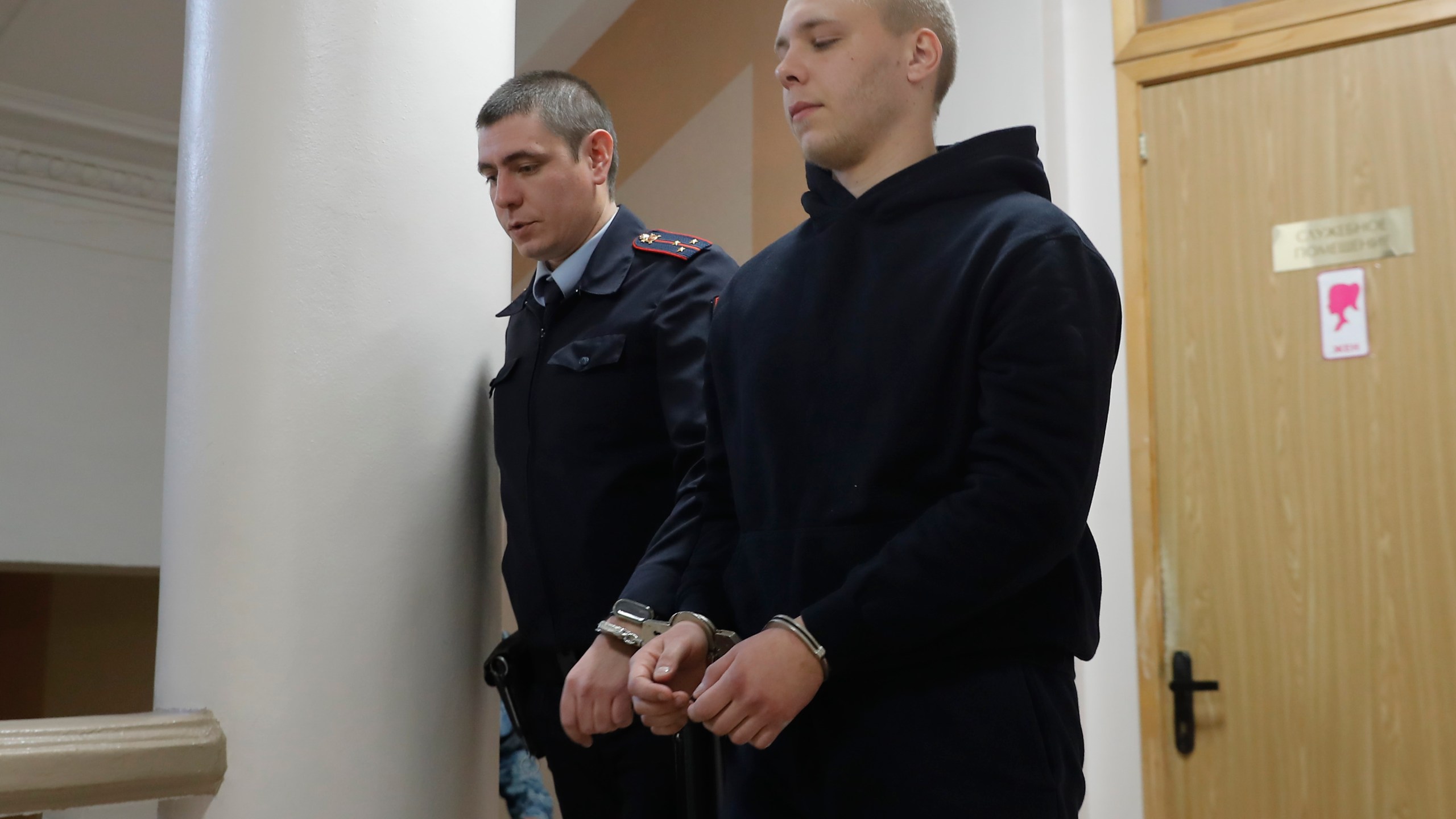 Nikita Zhuravel, right, is escorted by the police to a courtroom prior to a hearing of a treason case in Volgograd, Russia, Thursday, Nov. 14, 2024. (AP Photo)