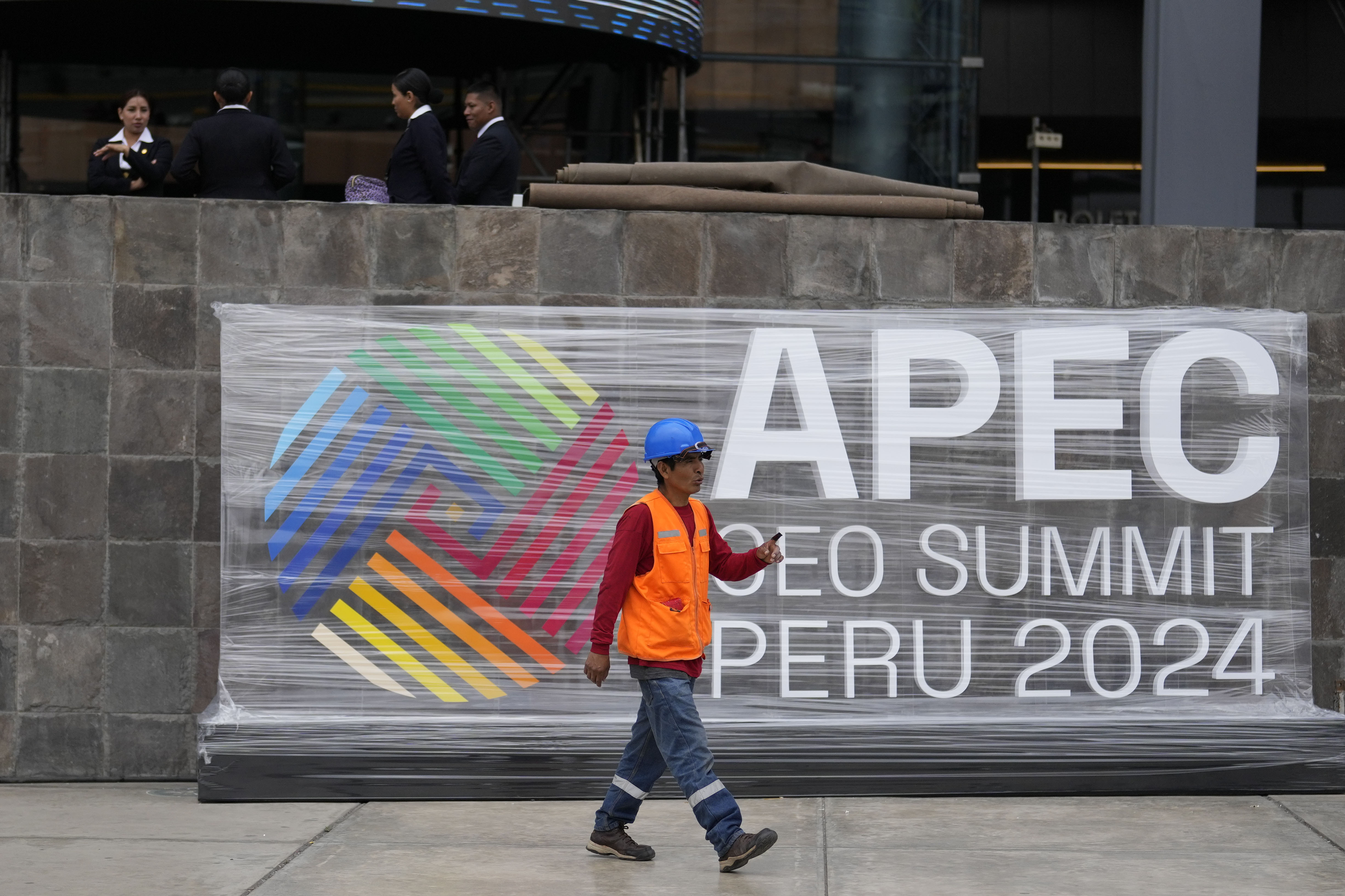 Un trabajador pasa junto a un cartel de la cumbre del foro Cooperación Económica Asia-Pacífico, APEC, en el exterior del Ministerio de Cultura, en Lima, Perú, el 12 de noviembre de 2024. (AP Foto/Fernando Vergara)