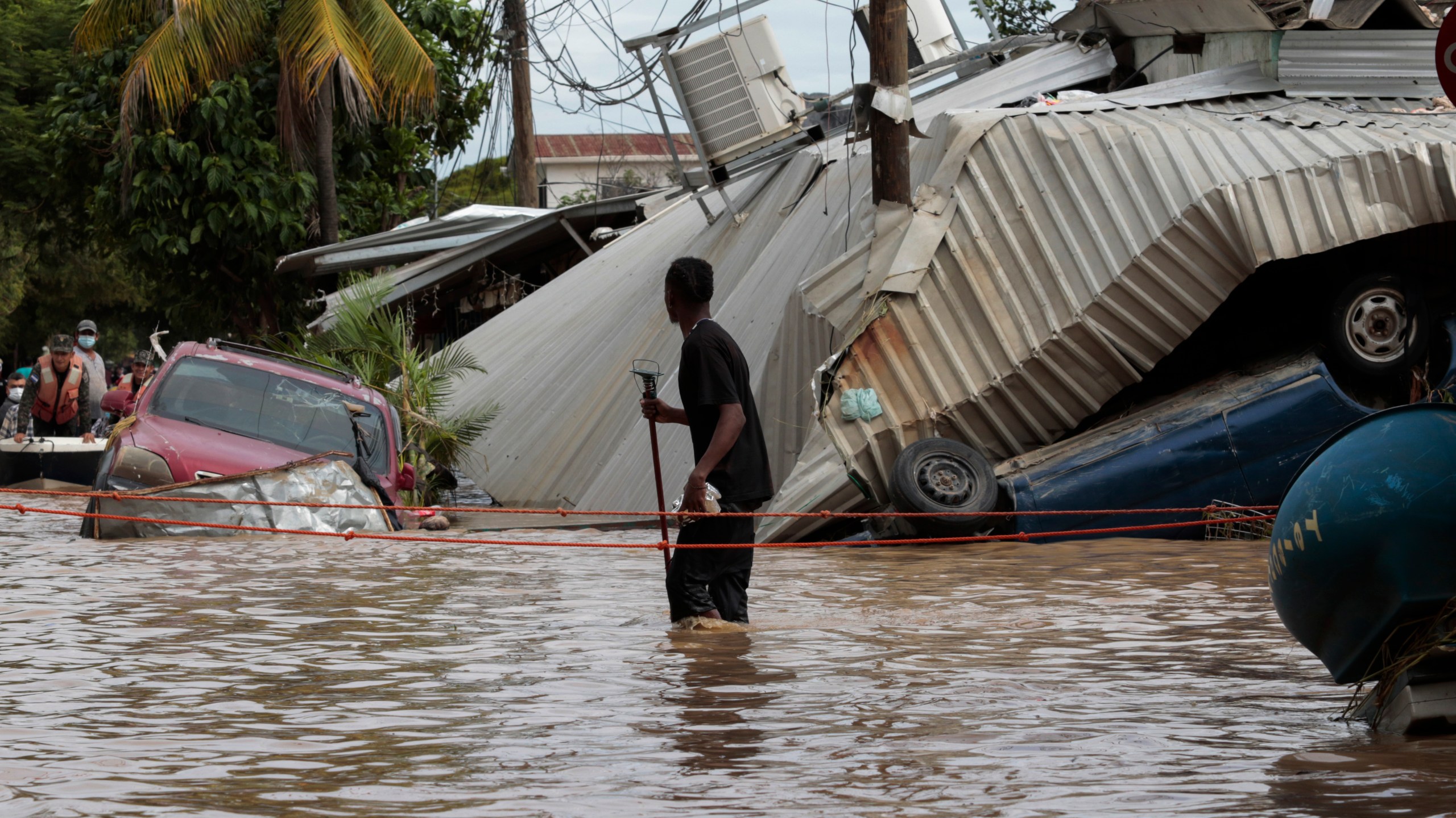 FILE - A resident walking through a flooded street looks back at storm damage caused by Hurricane Eta in Planeta, Honduras, Nov. 6, 2020. (AP Photo/Delmer Martinez, File)