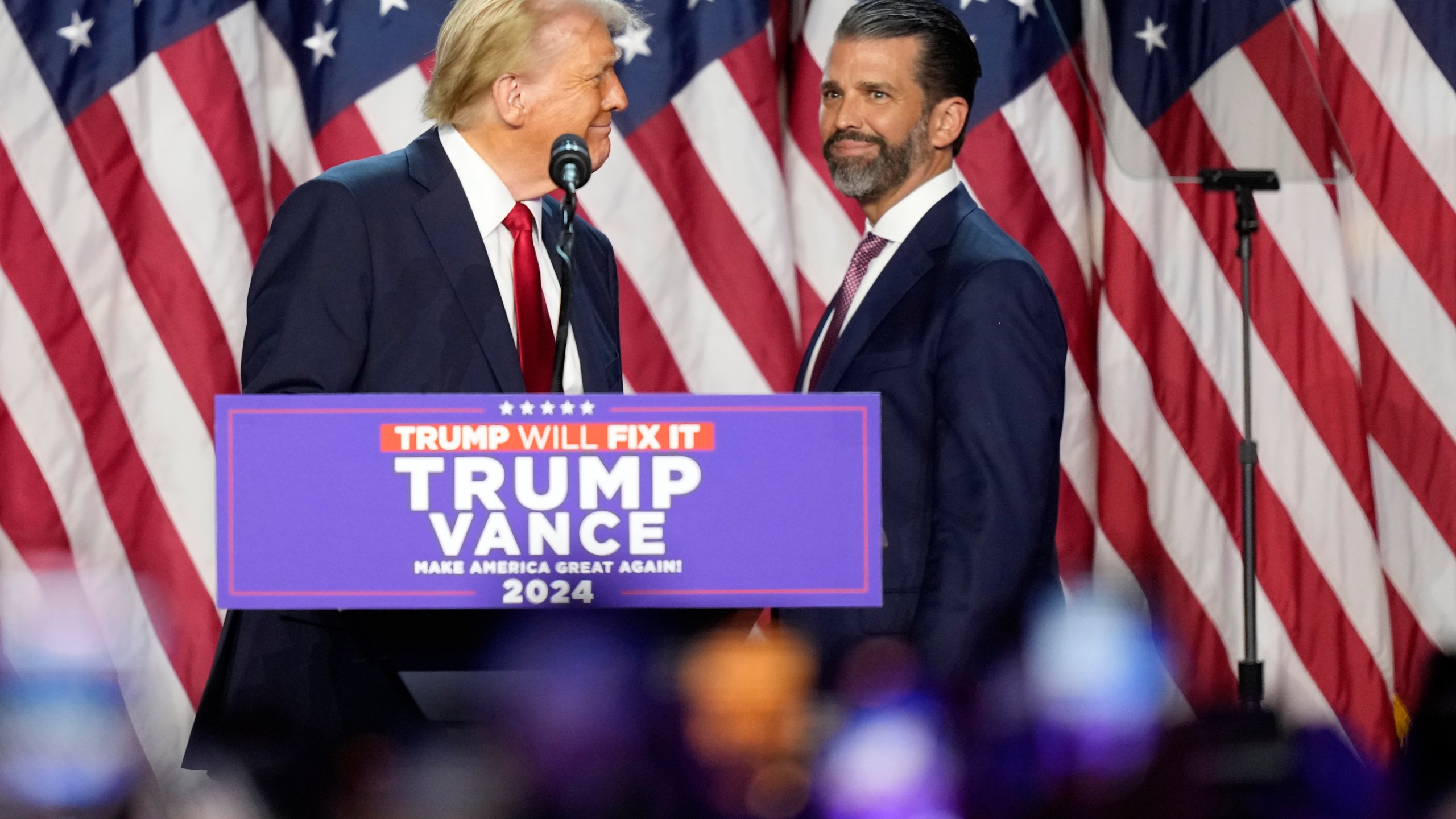 Republican presidential nominee former President Donald Trump, left, looks at his son Donald Trump Jr. at an election night watch party, Wednesday, Nov. 6, 2024, in West Palm Beach, Fla. (AP Photo/Alex Brandon)