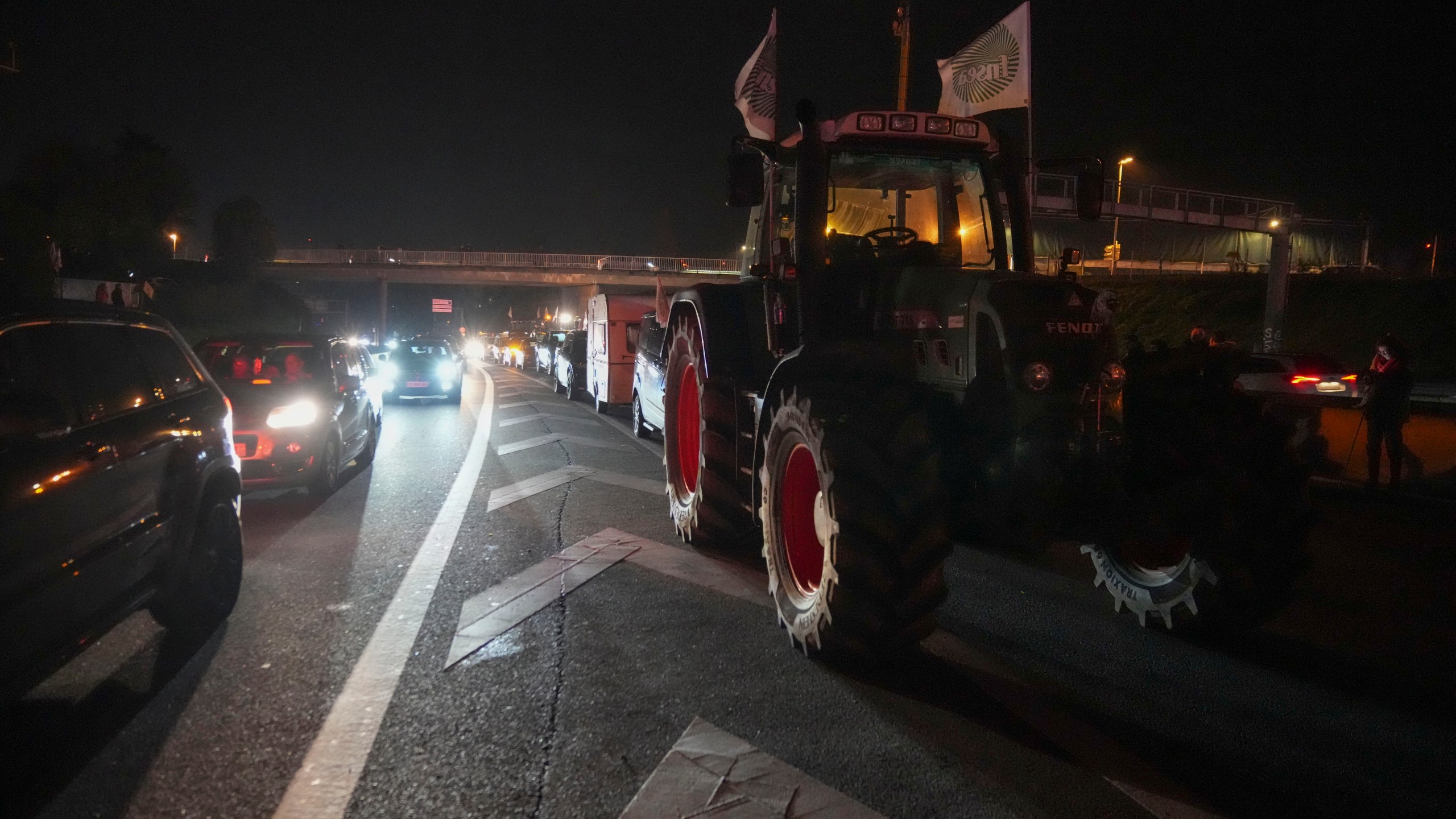 Cars drive along tractors on a blocked highway in Velizy-Villacoublay, outside Paris, Sunday, Nov. 17, 2024. (AP Photo/Michel Euler)