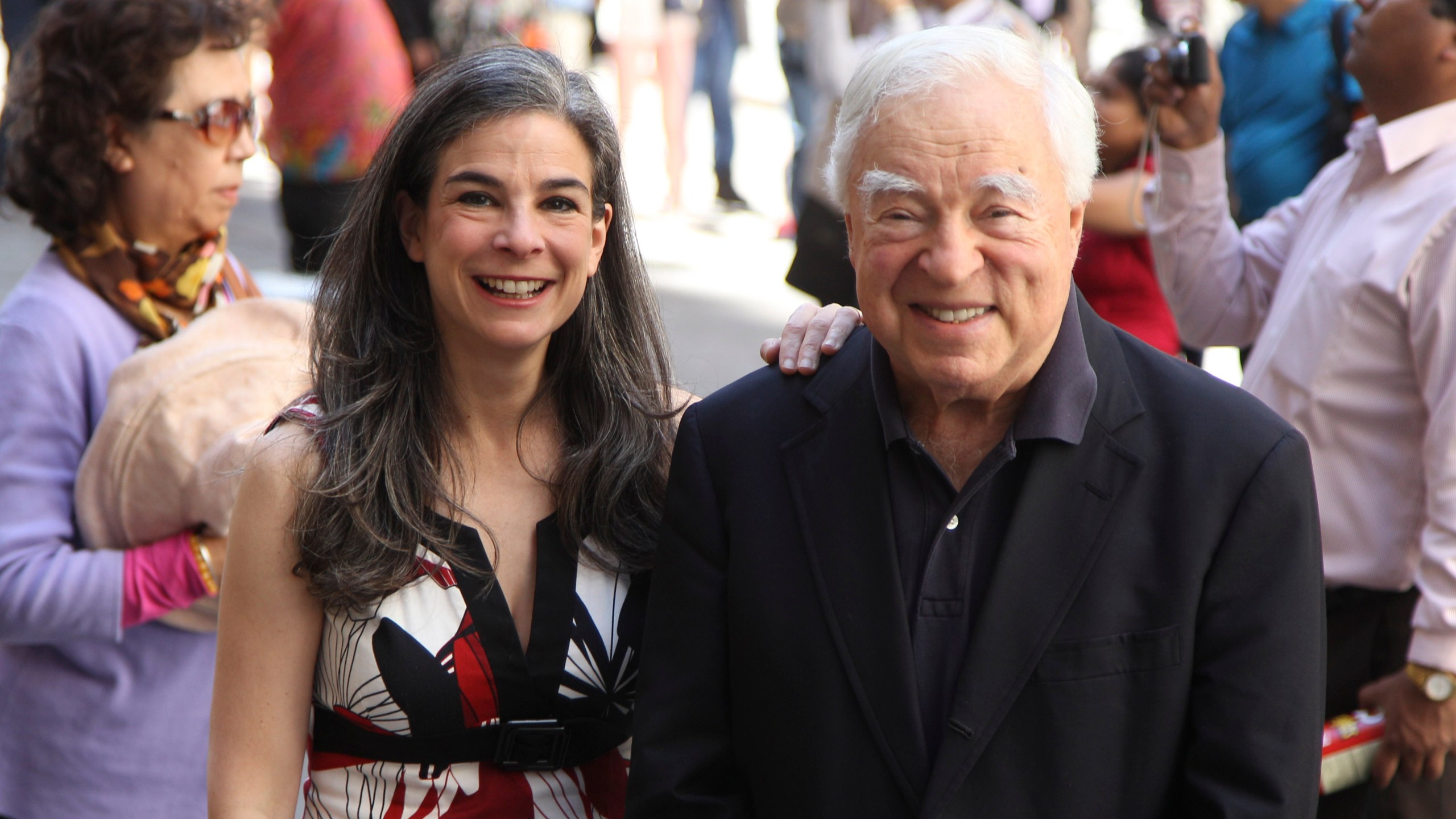 FILE - Arthur Frommer, 83, and his daughter, Pauline Frommer, 46, pose among tourists in the Wall Street area in New York, May 20, 2012. (AP Photo/Seth Wenig, File)